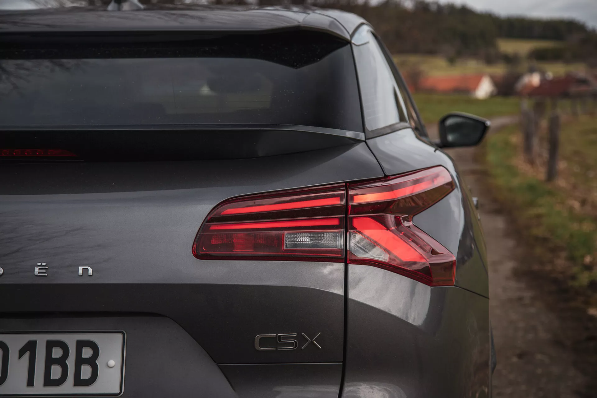 Section arrière du Citroen C5-X 2022 sous un angle oblique montrant les feux arrière LED, la finition brillante et le badge du modèle