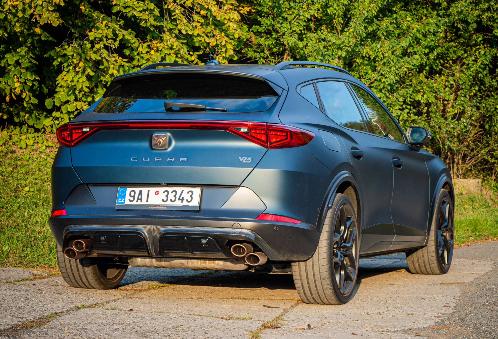 Vue arrière trois quarts de la Cupra Formentor 2020 mettant en lumière des caractéristiques sportives telles que des embouts d'échappement doubles, un aileron de toit et des roues en alliage, avec le badging de marque et modèle pendant la journée
