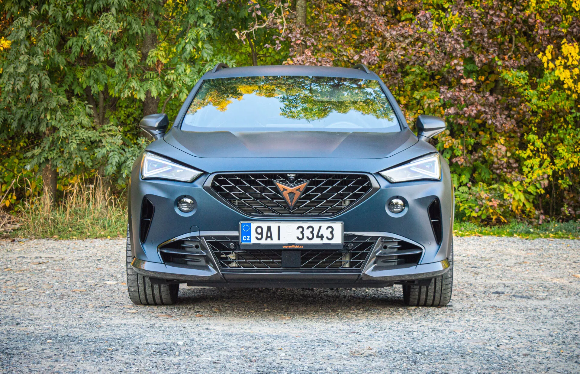 Vue frontale du Cupra Formentor 2020 montrant un design moderne, grande calandre avec emblème, motif géométrique de la grille, phares LED élégants, feux de brouillard, pare-chocs avant sportif avec de grandes prises d'air, lignes de caractère sur le capot, plaque d'immatriculation européenne centrale et spoiler pour la performance aérodynamique.