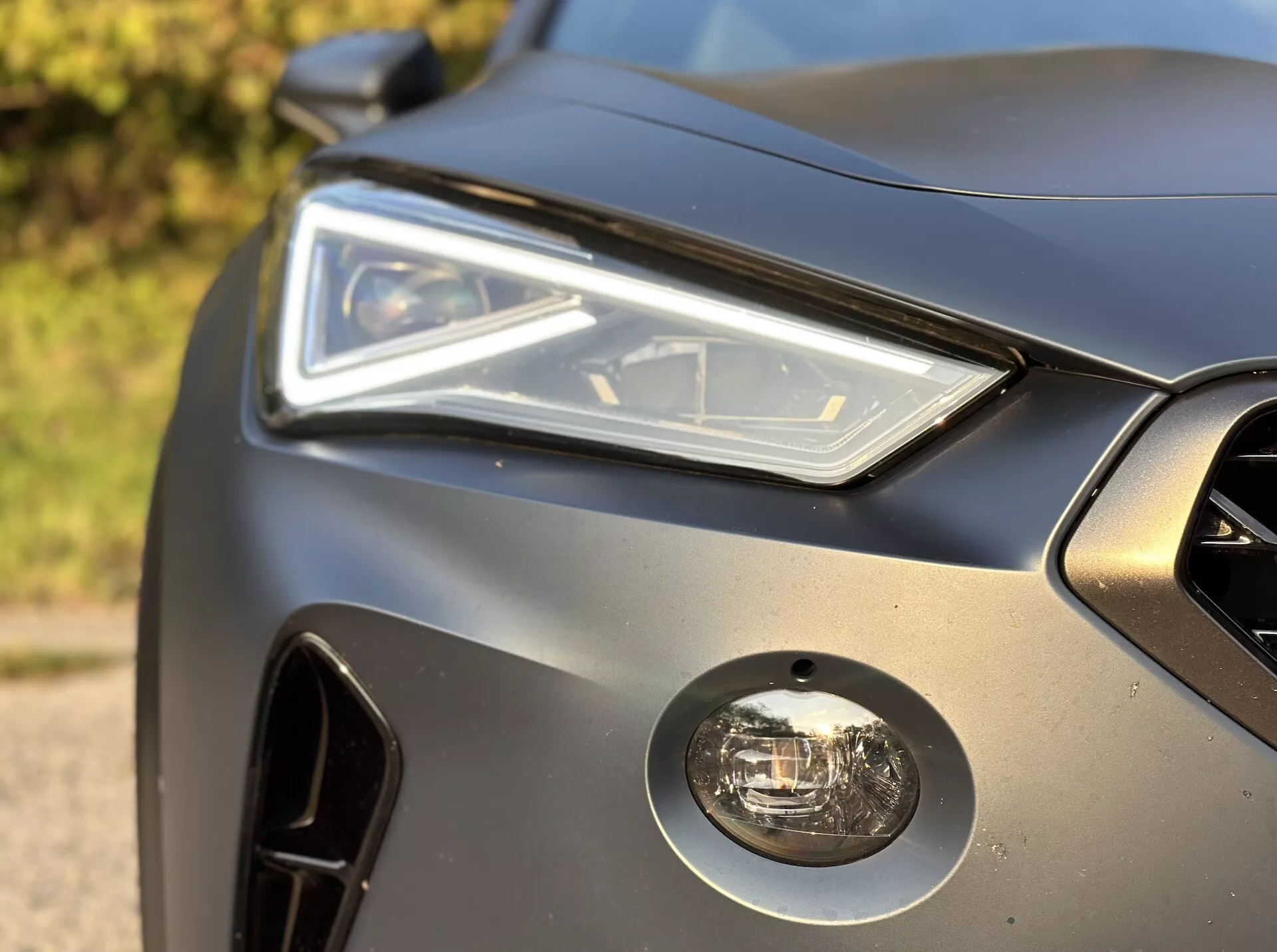Gros plan sur le coin frontal du Cupra Formentor 2020 présentant l'ensemble de projecteur LED, le feu de brouillard, la grille avant et le design élégant du panneau de carrosserie avec finition mate