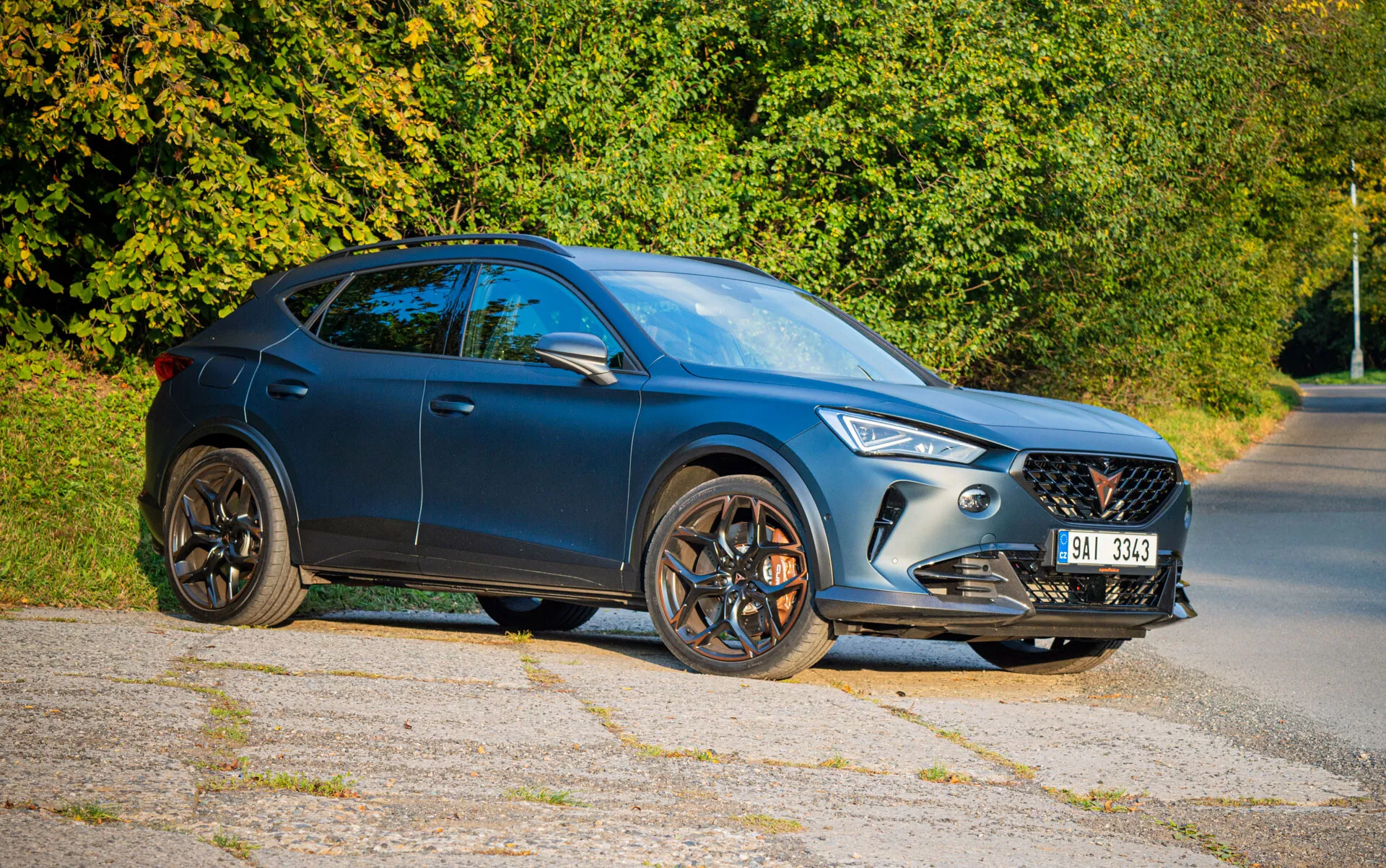 SUV crossover Cupra Formentor 2020 en bleu foncé, présentant un design élégant, des phares LED et des jantes en alliage à cinq branches, photographié sous un angle avant de trois quarts sur une route de banlieue
