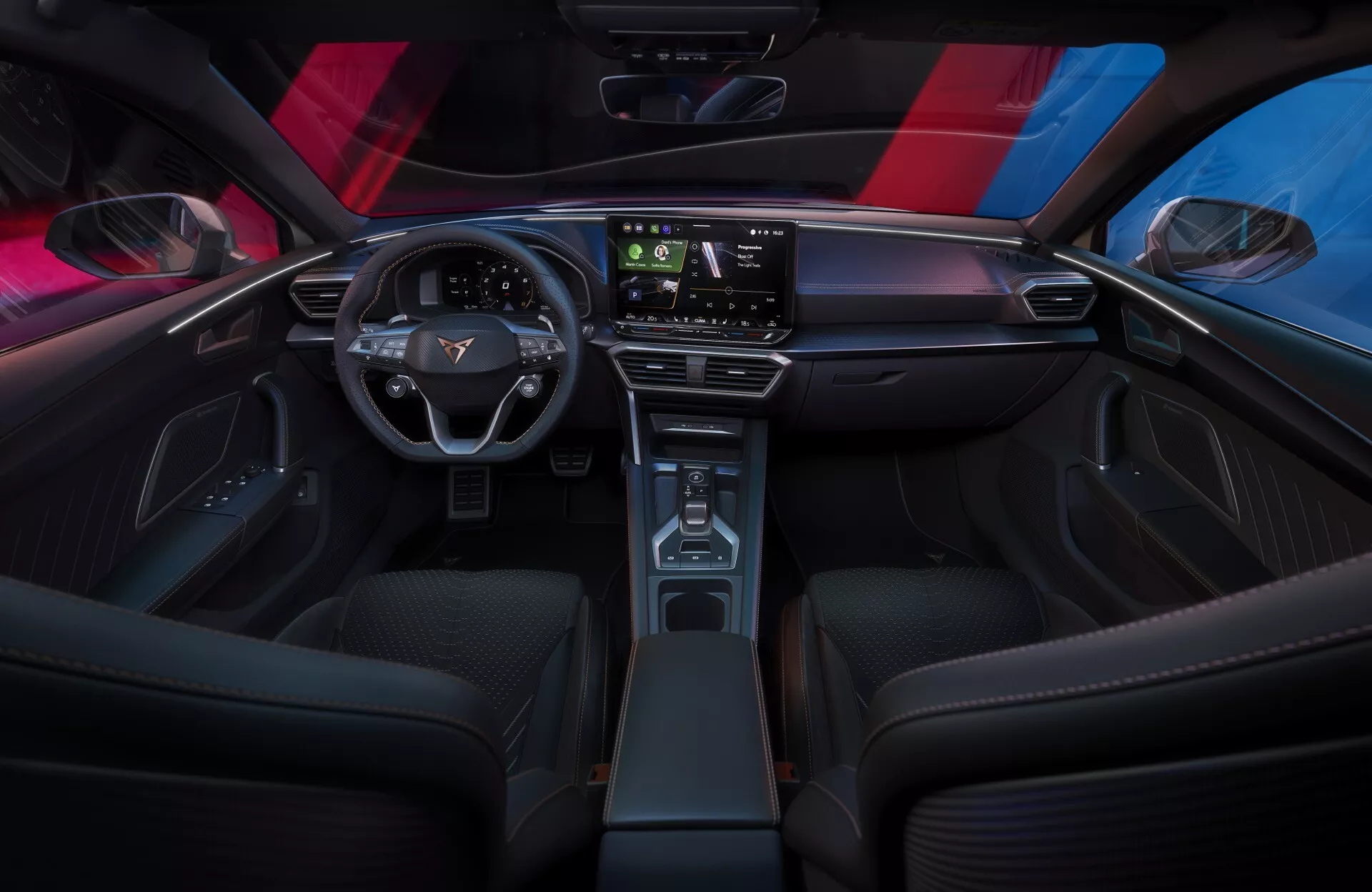 Vue intérieure de la Cupra Leon 2024 (restylage de première génération) depuis une perspective de siège arrière mettant en avant le tableau de bord élégant et minimaliste avec un grand écran tactile, le volant moderne à deux branches avec des commandes de véhicule et la console centrale étroite avec un décor en bois. Les sièges avant sportifs, l'éclairage d'ambiance et le toit panoramique rehaussent l'atmosphère sophistiquée et technologique de l'habitacle.