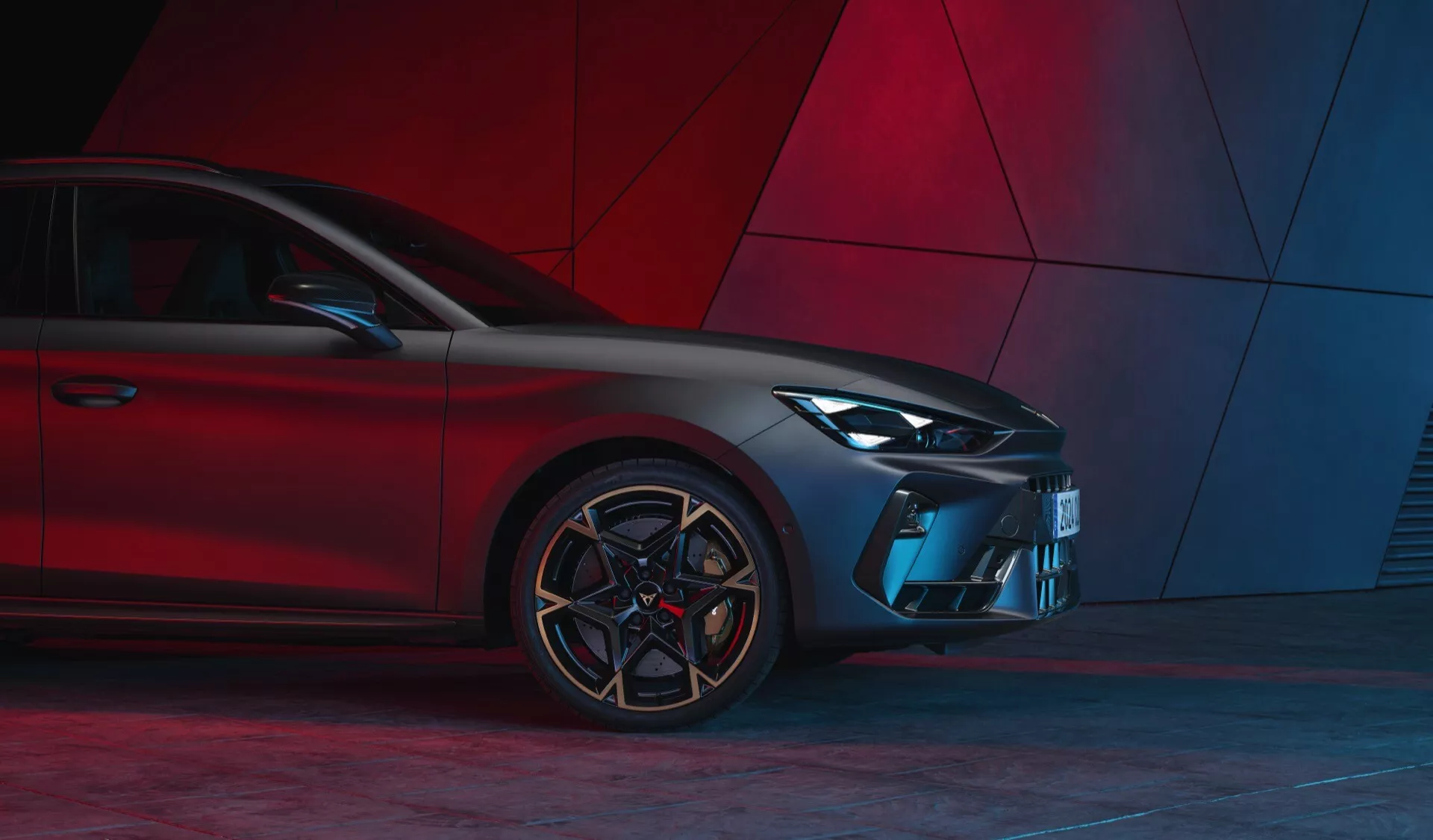 Vue avant trois quarts de la Cupra Leon 2024 (restylage de la première génération) mettant en avant le design moderne avec des phares à LED, une calandre sportive, un pare-chocs sculpté, des prises d'air angulaires, des jantes en alliage multibranchées et des pneus à profil bas contre un fond abstrait rouge.