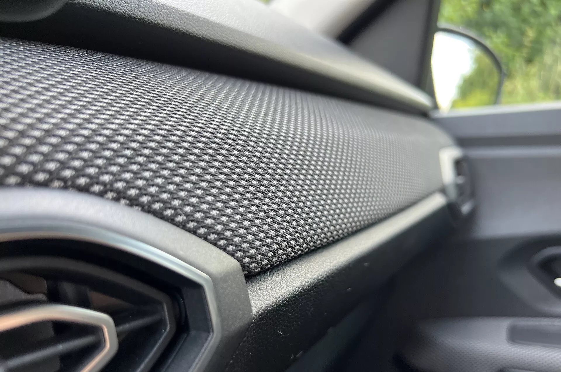 Vue rapprochée du tableau de bord côté passager de la Dacia Jogger 2022 avec motif en fibre de carbone et grille d'aération, soulignant la conception moderne et la finition de luxe