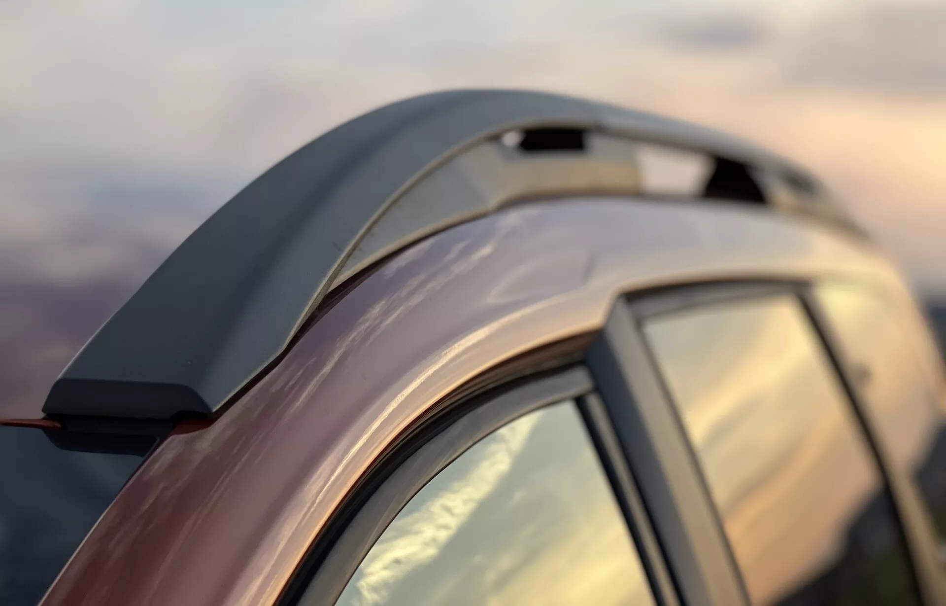 Gros plan sur la Dacia Jogger 2022 mettant en avant la ligne de toit élégante, les barres de toit aérodynamiques, l'aileron arrière intégré, la vitre arrière teintée avec montant C, la finition métallique réfléchissante et la qualité de construction précise