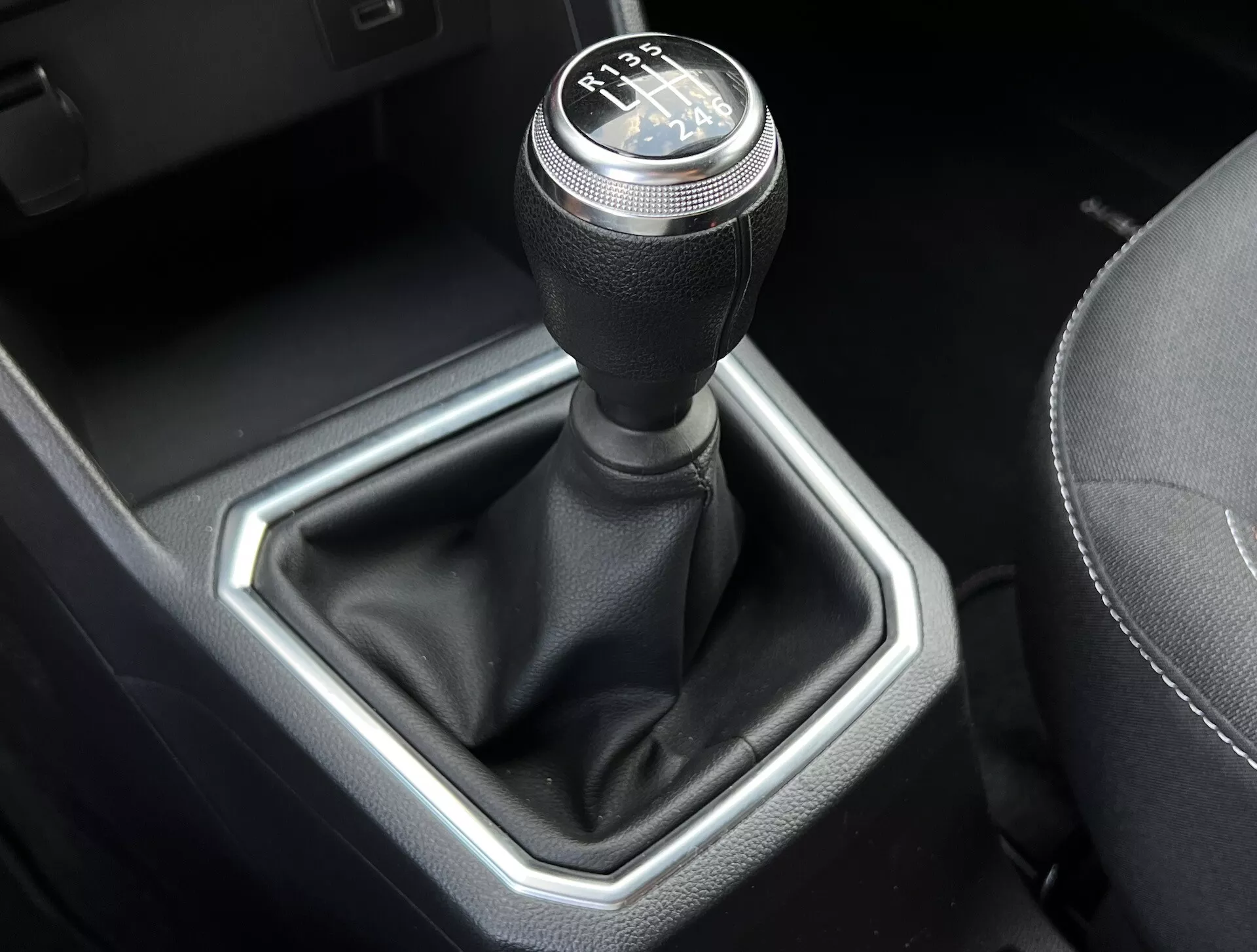 Vue rapprochée du levier de vitesse manuelle Dacia Jogger 2022, présentant un schéma de changement à 6 vitesses, levier recouvert de cuir et insert hexagonal métallique dans un intérieur de voiture raffiné