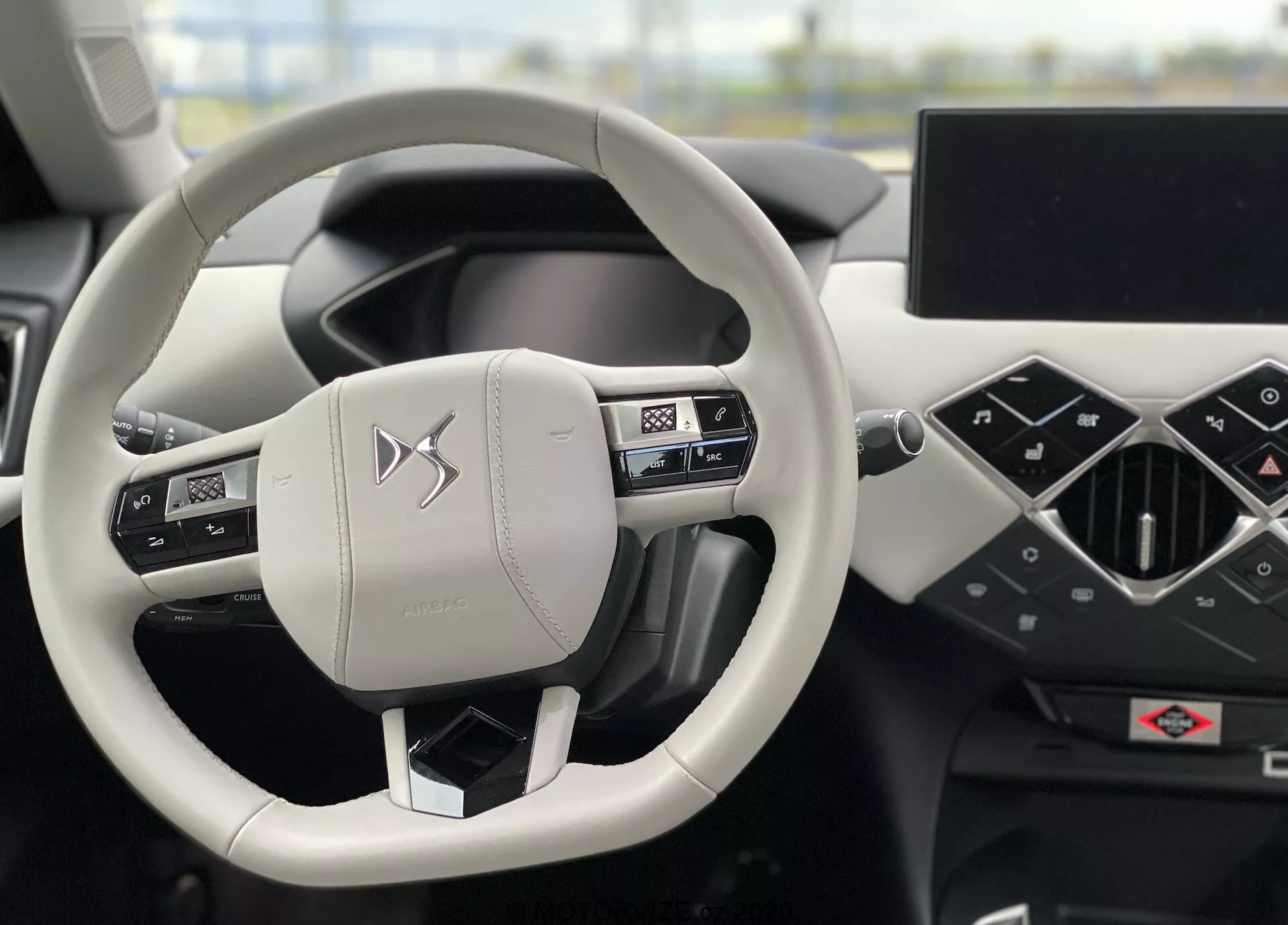 Vue intérieure de la DS Automobiles DS-3 Crossback E-Tense 2019 en mettant l'accent sur le volant et le tableau de bord depuis la perspective du conducteur. Le volant à deux branches, recouvert de cuir avec des coutures, comprend des commandes intégrées pour l'audio, le téléphone et les paramètres du véhicule. Le tableau de bord dispose d'un combiné d'instruments numériques et d'un grand écran d'infodivertissement horizontalement orienté. Le design minimaliste et moderne ainsi que les matériaux haut de gamme mettent en exergue une expérience de véhicule premium.