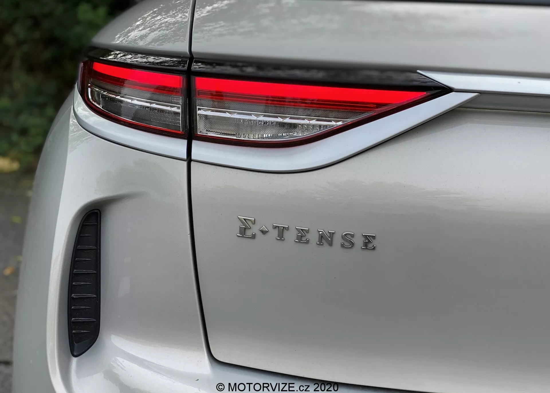 Gros plan sur la section arrière d'une DS Automobiles DS 3 Crossback E-Tense 2019 argentée moderne, présentant le feu arrière LED horizontal élégant, l'emblème E-TENSE sur le couvercle du coffre et la finition brillante de la peinture avec des reflets. Élément de design ou aération visible près de l'aile, soulignant le design automobile, la technologie et les caractéristiques écologiques.