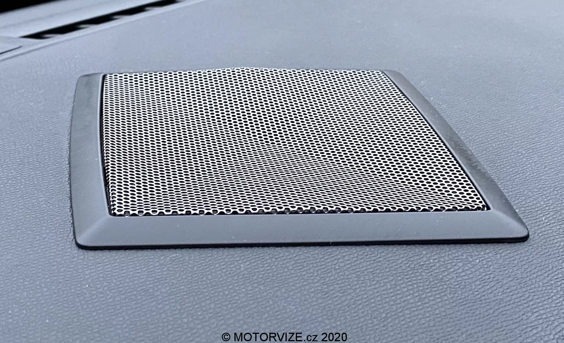 Vue en gros plan de la grille du haut-parleur sur le tableau de bord du véhicule DS Automobiles DS-3 Crossback modèle 2019. La grille trapézoïdale est dotée d'un maillage serré pour protéger le haut-parleur et d'un bord élégant et non réfléchissant s'intégrant au tableau de bord.