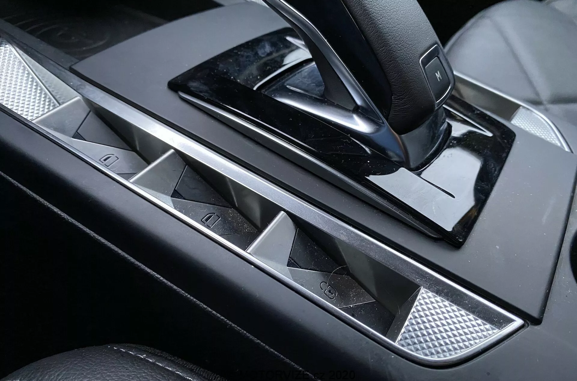 Vue rapprochée du panneau de commande de la porte conducteur de la luxueuse DS Automobiles DS-3 Crossback 2019, avec poignée de porte métallique élégante, boutons de vitres électriques avec accents chromés, joystick pour réglages des rétroviseurs latéraux, finition noire brillante et insert texturé en maille métallique pour une touche de sophistication.