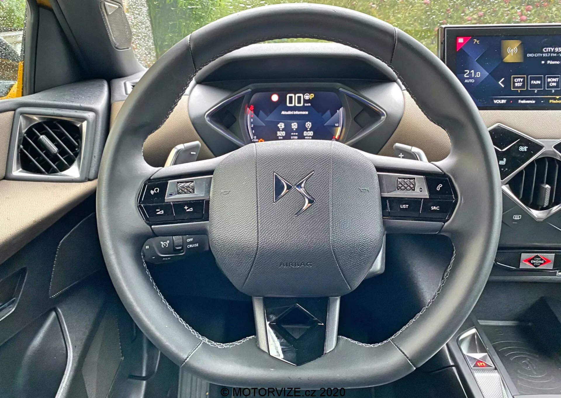 Vue à la première personne depuis le siège du conducteur d'une DS-Automobiles DS-3 2019 (DS-3 Crossback), centrée sur un volant à trois branches en cuir avec commandes intégrées et palettes de changement de vitesse. Le tableau de bord numérique affiche des informations essentielles, mettant en avant la technologie avancée du véhicule. Un système d'infodivertissement à écran tactile sur la console centrale indique des fonctionnalités de confort haut de gamme.