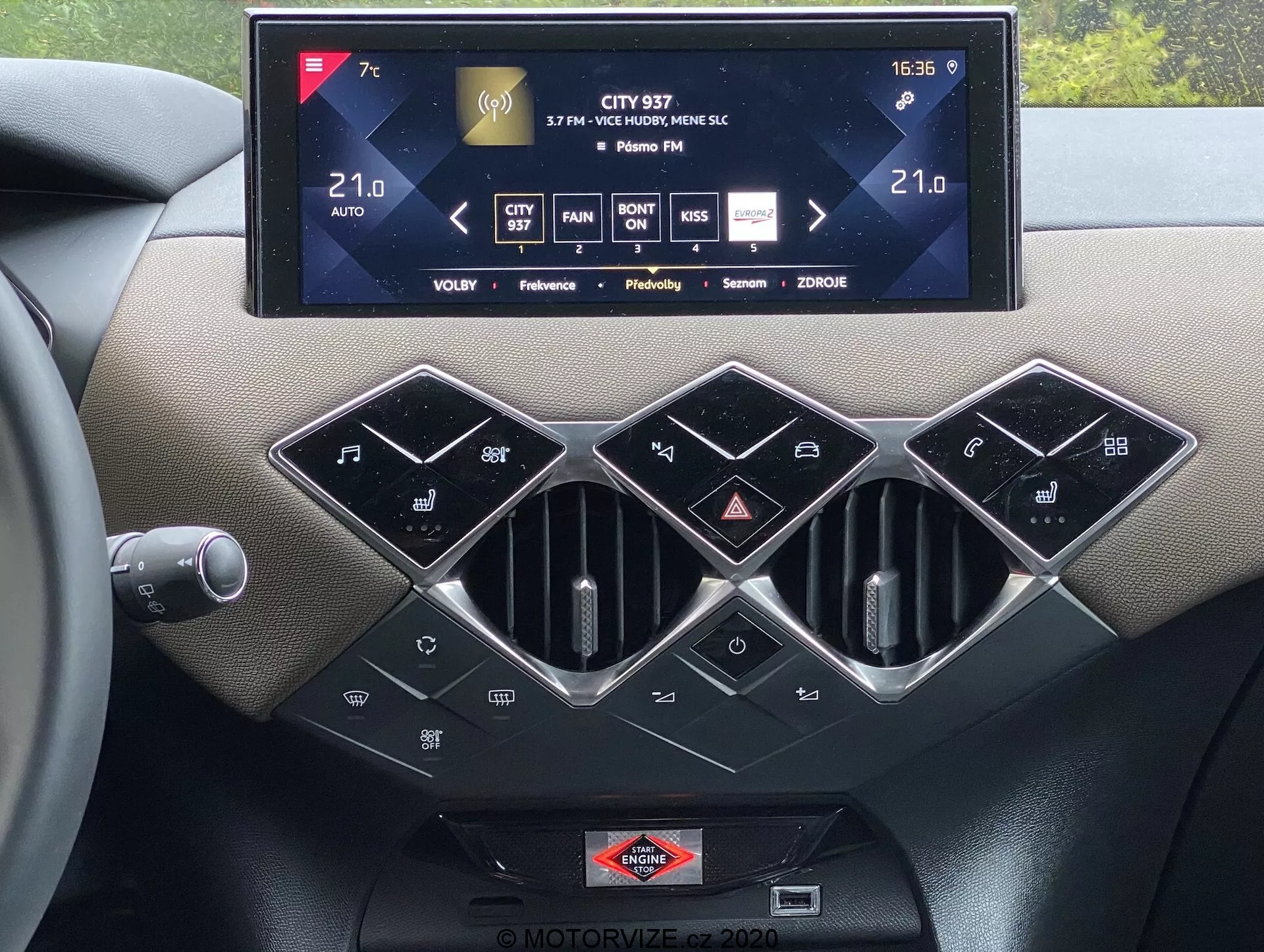 Vue intérieure de la console centrale du ds-automobiles ds-3 2019 montrant un grand système d'info-divertissement à écran tactile affichant le contrôle de la climatisation, les informations radio et les paramètres, avec trois bouches d'aération hexagonales à garniture argentée en dessous. Il y a une rangée de boutons de contrôle de la climatisation noirs brillants, y compris SYNC pour le contrôle de la climatisation multizone, des capacités de contrôle de la climatisation automatique et un badge de marque positionné sous l'écran tactile, mettant en valeur des matériaux tactiles premium et une technologie automobile moderne