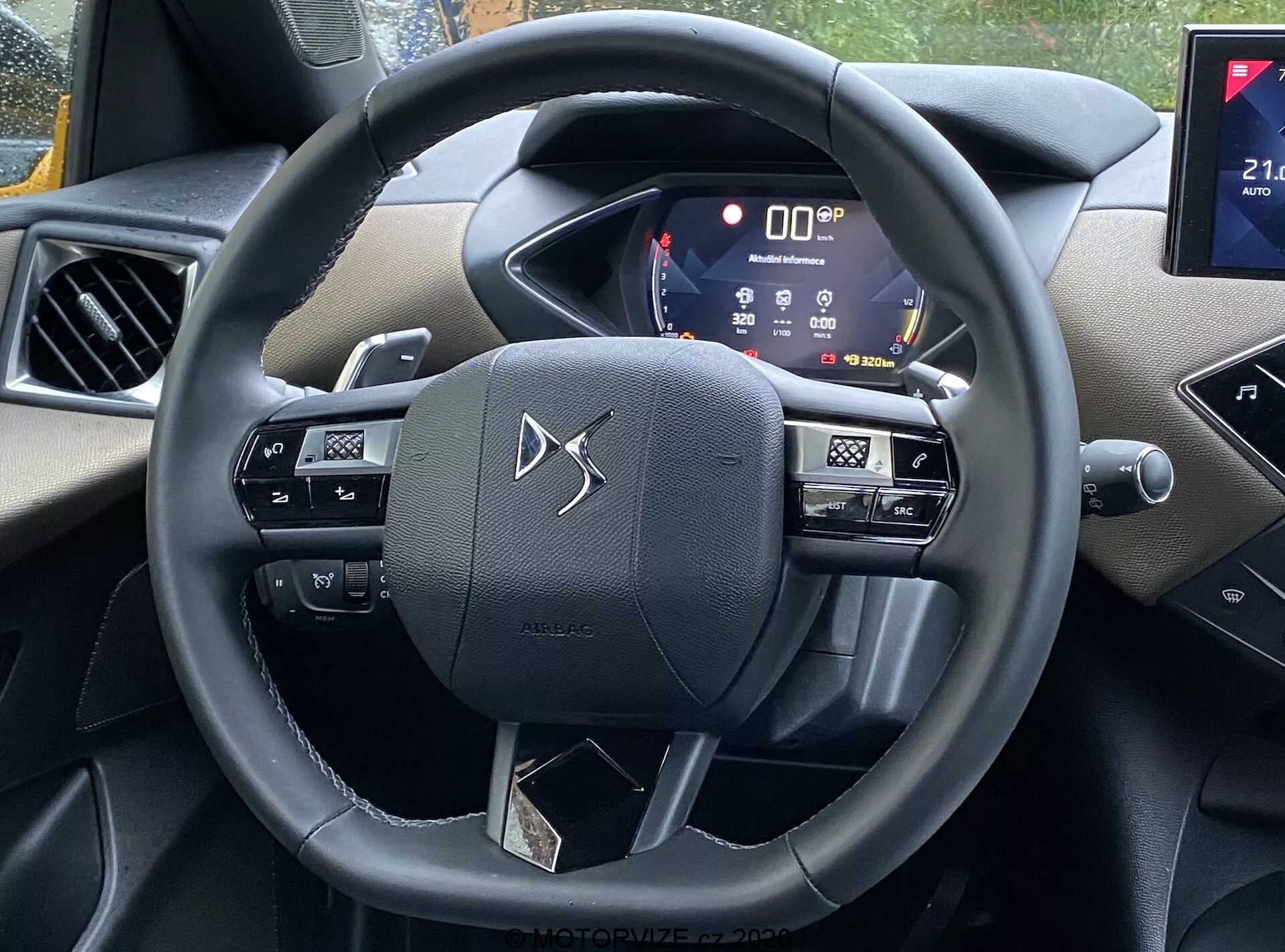 Vue intérieure de la voiture DS Automobiles DS-3 2019 (DS-3 Crossback) depuis la perspective du siège du conducteur, mettant en avant le volant avec des boutons de commande multimédia, de commande vocale et de régulateur de vitesse, un tableau de bord numérique affichant diverses informations sur le véhicule, et une partie du système d'infodivertissement avec une connectivité potentielle pour smartphone et des capacités de navigation. L'intérieur comprend un mélange de plastiques doux au toucher et d'accents chromés, démontrant une technologie moderne et une esthétique attrayante.