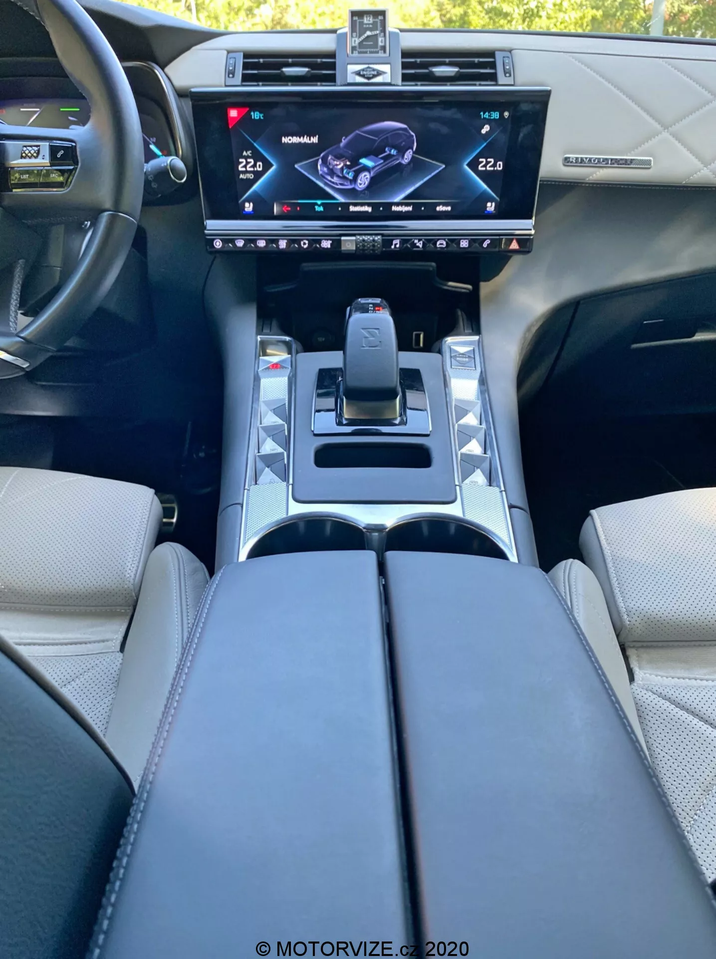 Vue intérieure de la DS Automobiles DS 7 Crossback 2018 depuis le siège du conducteur, mettant en avant la console centrale avec un écran tactile infotainment haute résolution, sélecteur de vitesse moderne, boutons de modes de conduite, porte-gobelets, accoudoirs rembourrés et volant avec des boutons de commande, reflétant un design automobile et une technologie de pointe.