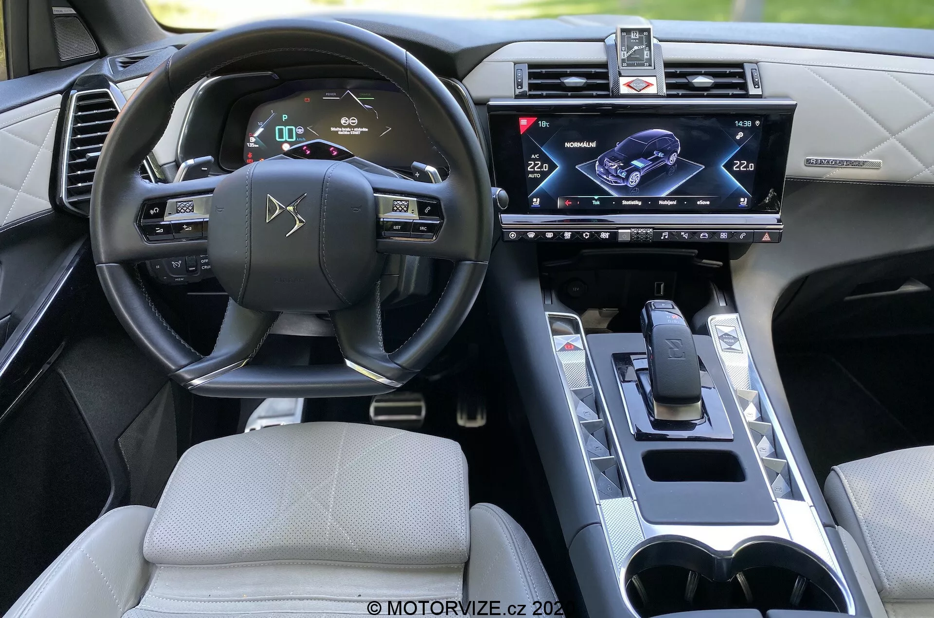 Intérieur de la DS Automobiles DS 7 Crossback 2018, vue depuis le siège arrière avec focus sur le côté conducteur. Caractéristiques comprennent volant avec commandes intégrées, tableau de bord numérique, système d'infodivertissement à écran tactile monté au centre, levier de vitesse moderne, porte-gobelets et design intérieur sophistiqué avec commodités technologiques avancées.
