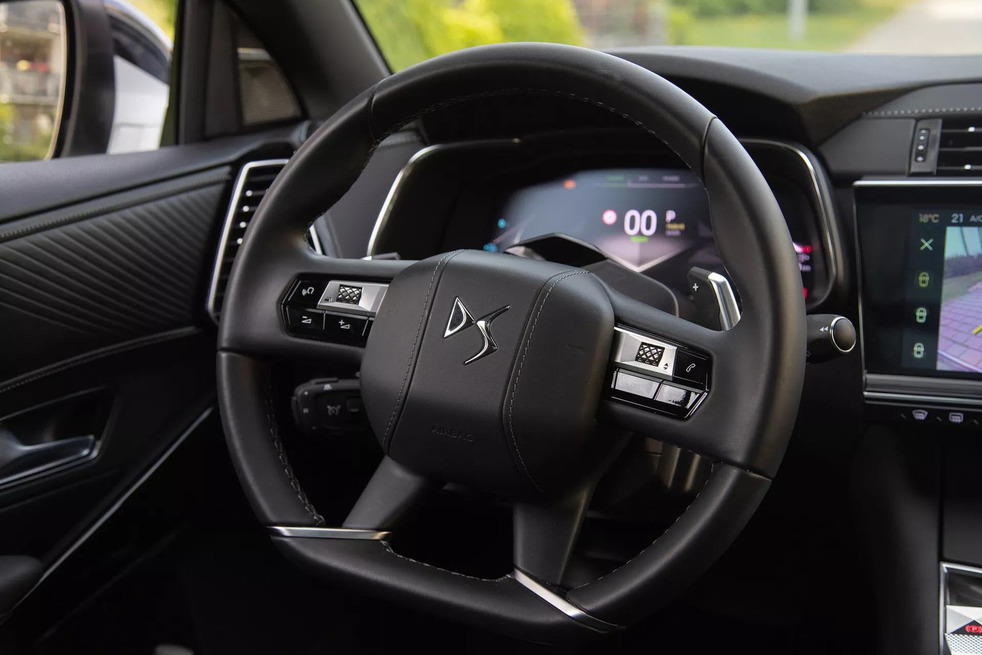Vue intérieure de la DS Automobiles DS-7 2022 affichant le volant avec des boutons multifonctions et le tableau de bord numérique, incluant les palettes de changement de vitesse et une partie du système d'infodivertissement montrant la navigation