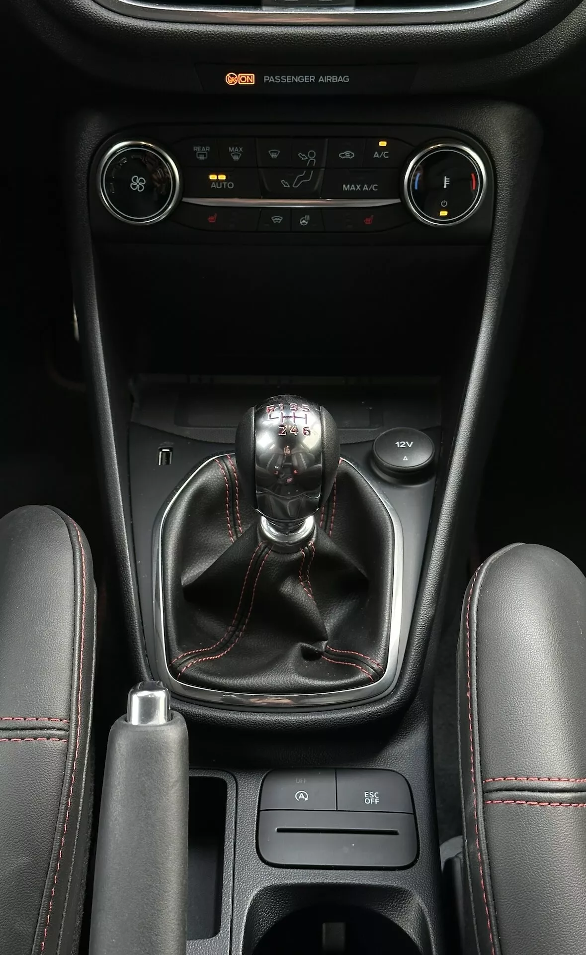 Console centrale du Ford Fiesta 2022 avec contrôle climatique, levier de vitesse manuel, sélecteur de mode de conduite, et compartiments de rangement