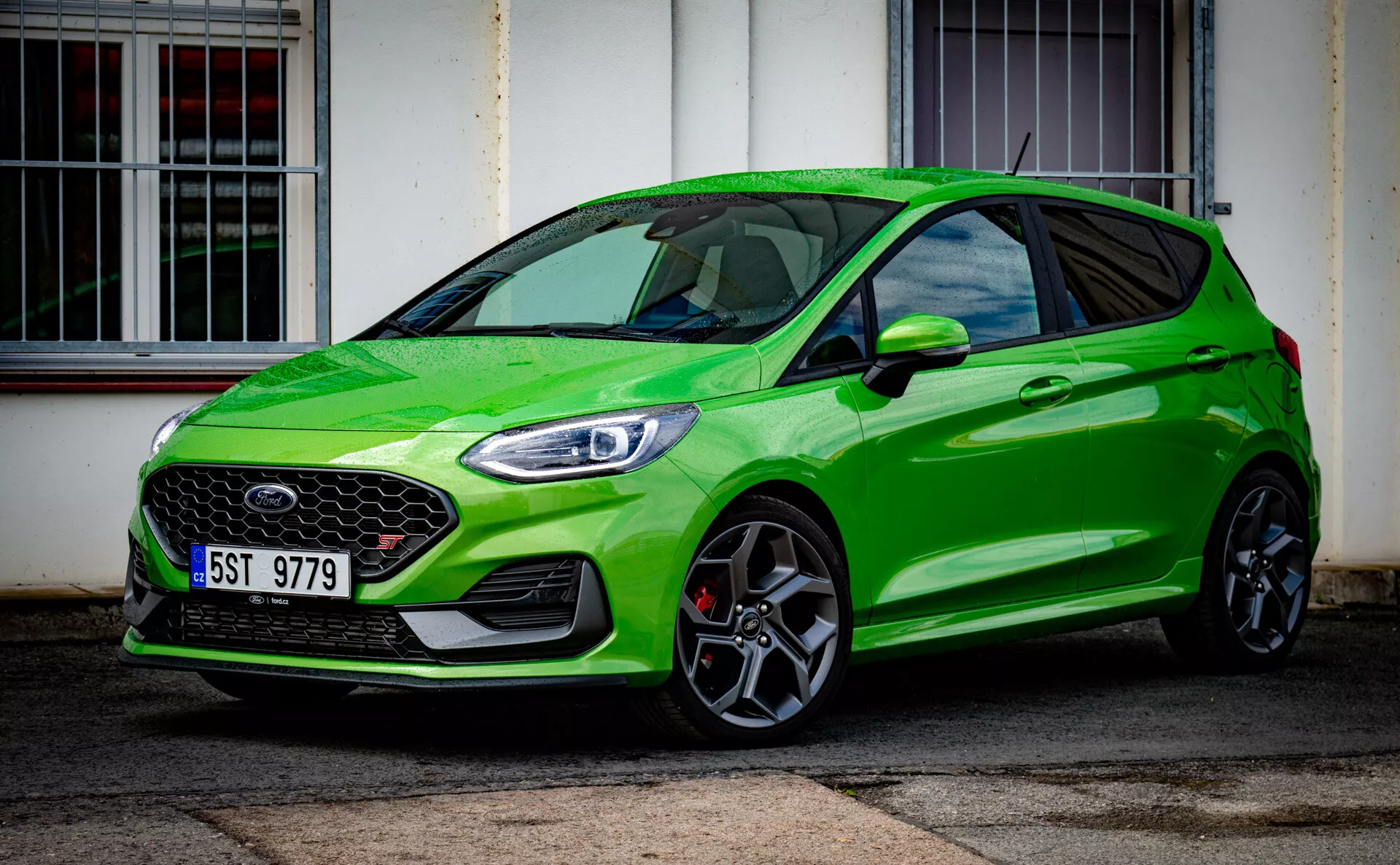 Ford Fiesta vert brillant modèle hatchback moderne 2022 soulignant la stature sportive avec une grille avant proéminente et des phares avant élégants LED, garée en diagonale devant un bâtiment