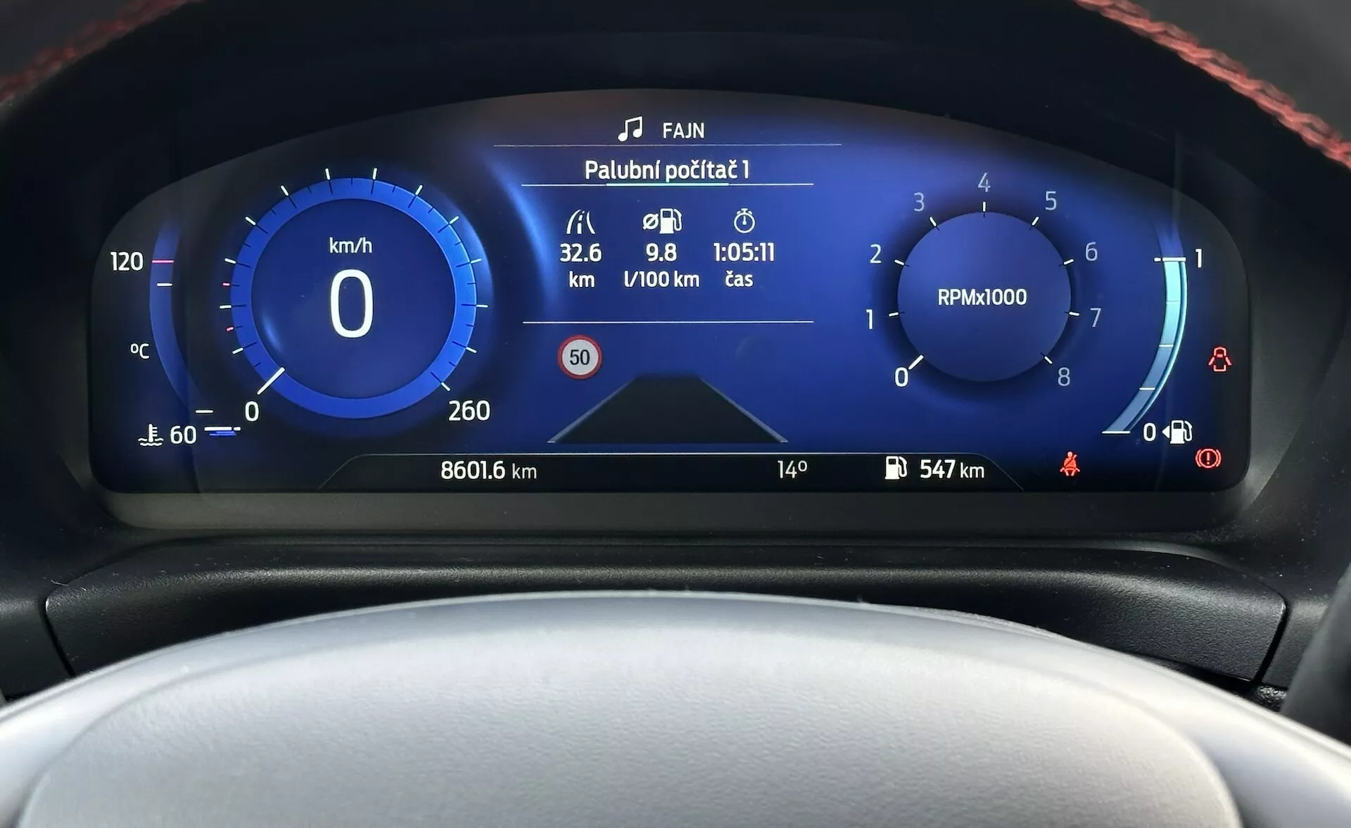 Tableau de bord numérique du Ford Fiesta 2022 présentant une vue frontale rapprochée avec un compteur de vitesse, un compte-tours, un jauge d'efficacité énergétique et divers indicateurs d'état du véhicule dans un design moderne aux couleurs bleues et blanches.