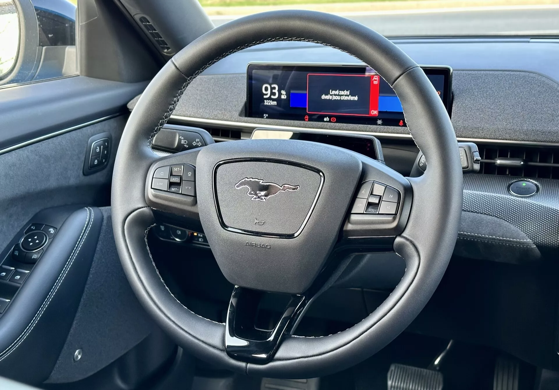 Intérieur du Ford Mustang Mach-E 2020 mettant en vedette le volant moderne à trois branches avec boutons multifonctions et le cluster d'instruments numériques du point de vue du conducteur, montrant les commandes, l'emblème et des indices de navigation.