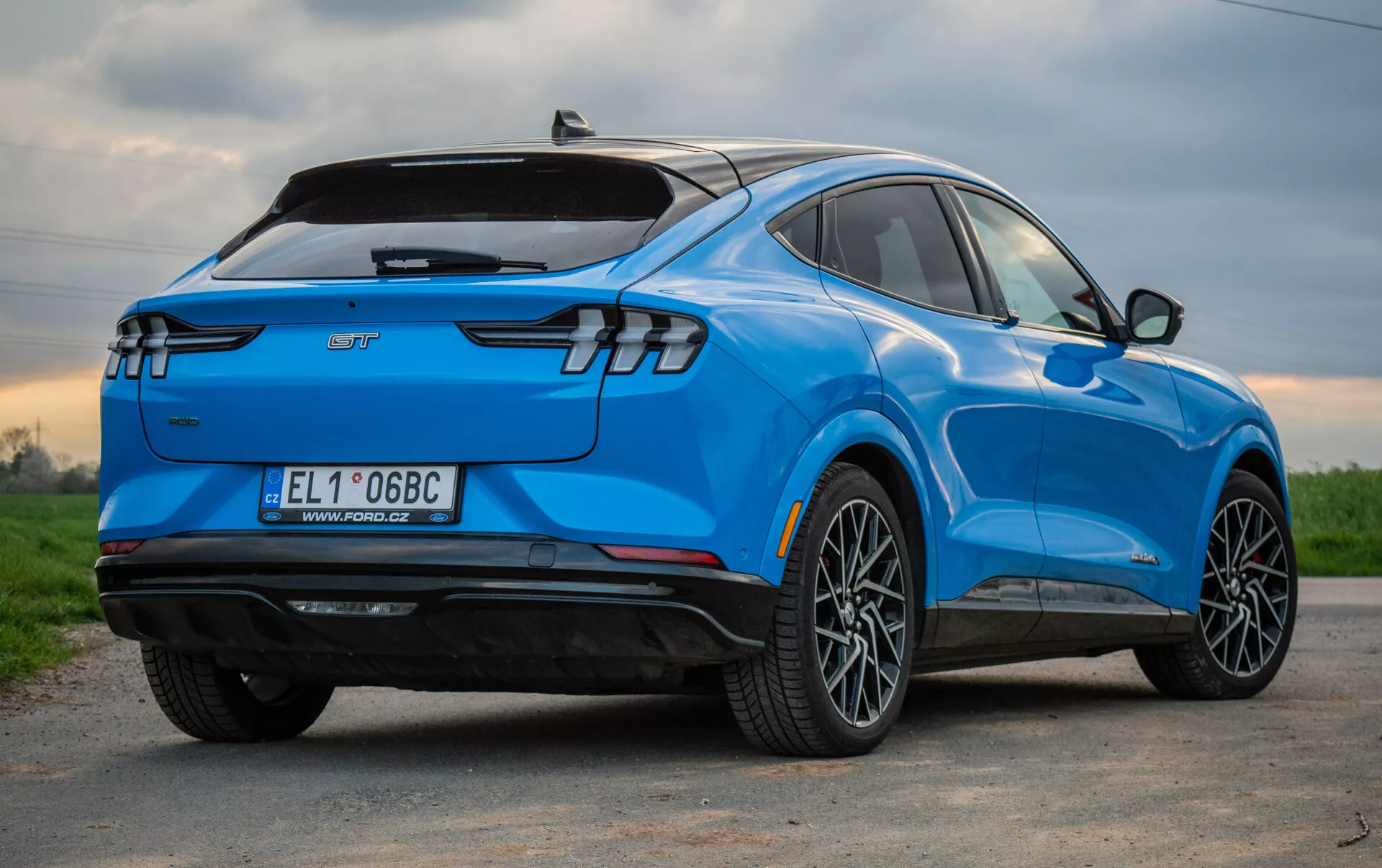 SUV électrique bleu Ford Mustang Mach-E 2020 vu d'une perspective arrière aux trois quarts, mettant en évidence son design aérodynamique élégant, ses feux arrière LED modernes, ses roues en alliage à multiples branches, son badge de véhicule électrique et ses caractéristiques technologiques