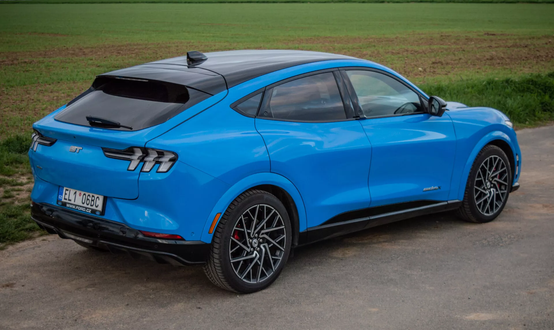 SUV électrique Ford Mustang Mach-E 2020 bleu vif dans une vue arrière dynamique à trois quarts soulignant un design aérodynamique, des feux arrière élégants et des roues en alliage sportives, mettant en avant la technologie avancée et la propulsion électrique.