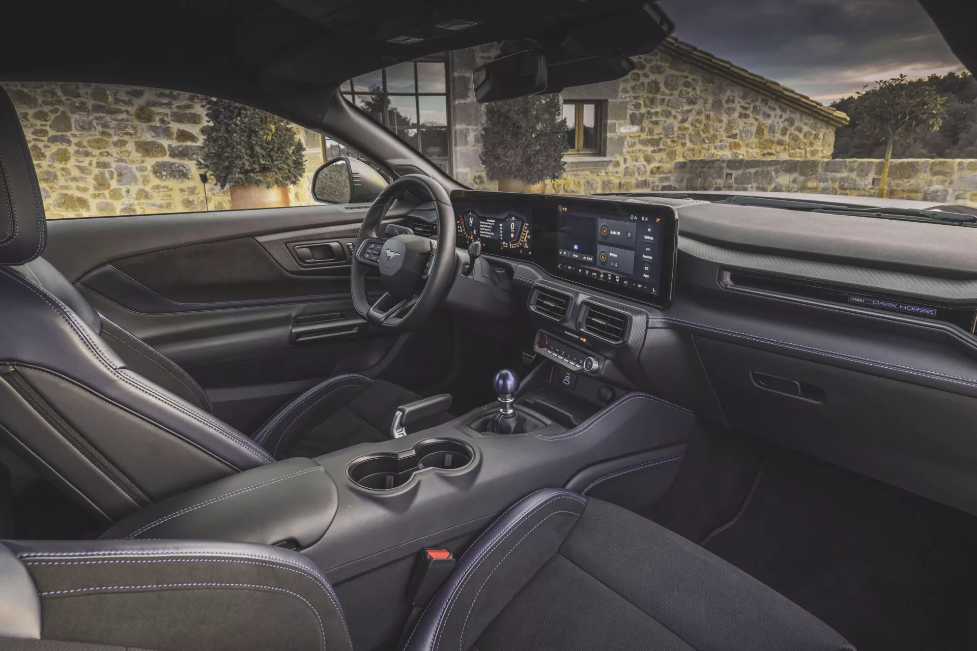 Vue intérieure de la Ford Mustang de 2nde génération 2024 depuis l'arrière, montrant le tableau de bord, l'infodivertissement à écran large, les sièges sportifs et les fonctionnalités de confort avancées