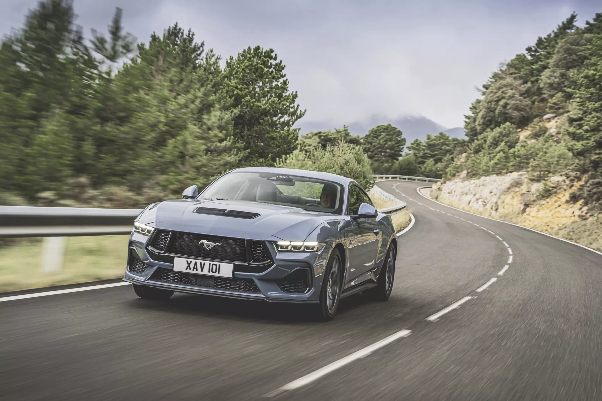 Ford Mustang de 2e génération 2024 en mouvement sur une route sinueuse, présentant une vue avant trois quarts, posture dynamique, design agressif et caractéristiques de performance