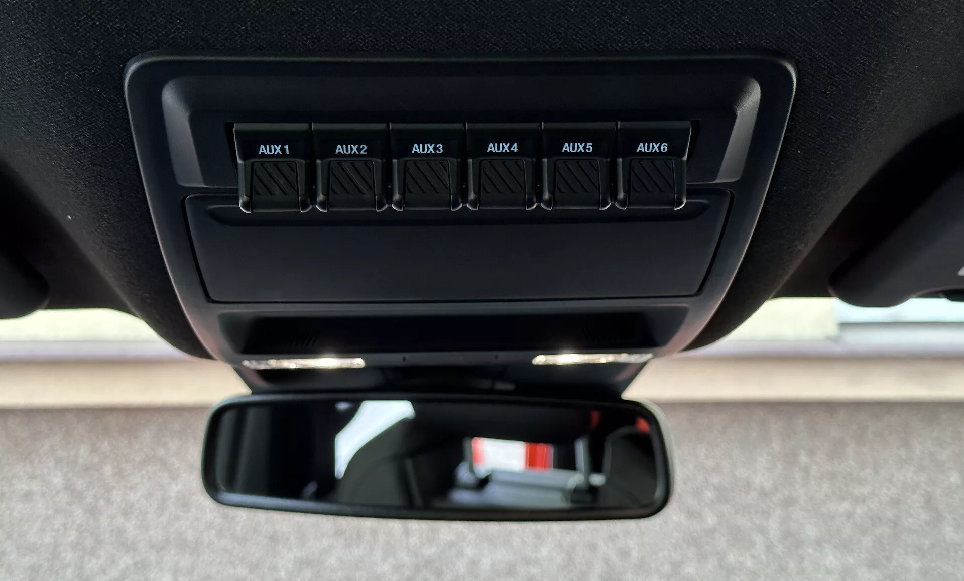 Vue rapprochée à l'intérieur d'un Ford Ranger 2022, se concentrant sur les interrupteurs auxiliaires étiquetés de AUX1 à AUX6 sur la console de toit et le rétroviseur standard du point de vue du conducteur