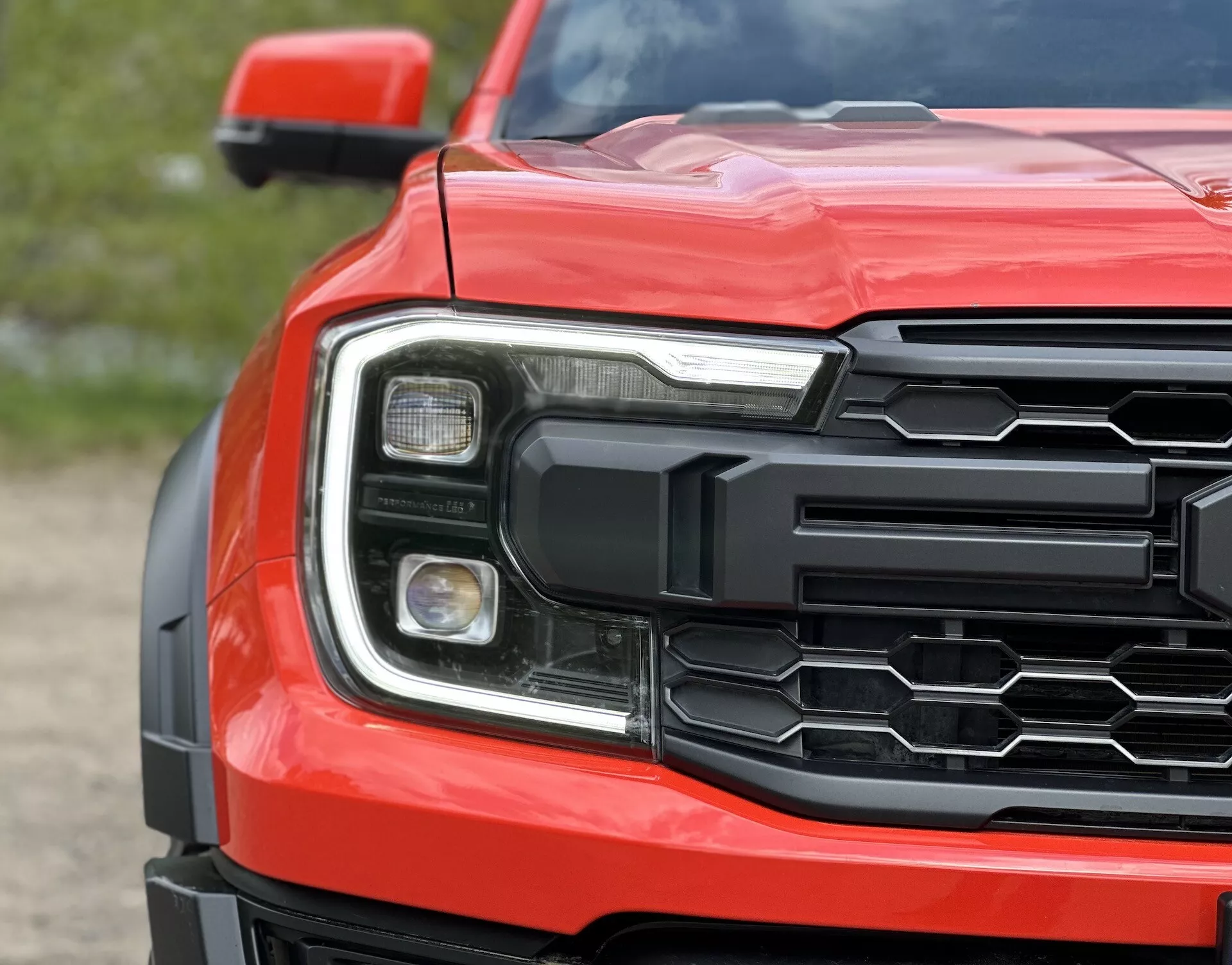 Vue rapprochée du coin avant du Ford Ranger 2022 montrant la grille hexagonale, l'ensemble phare détaillé et le capot profilé en rouge