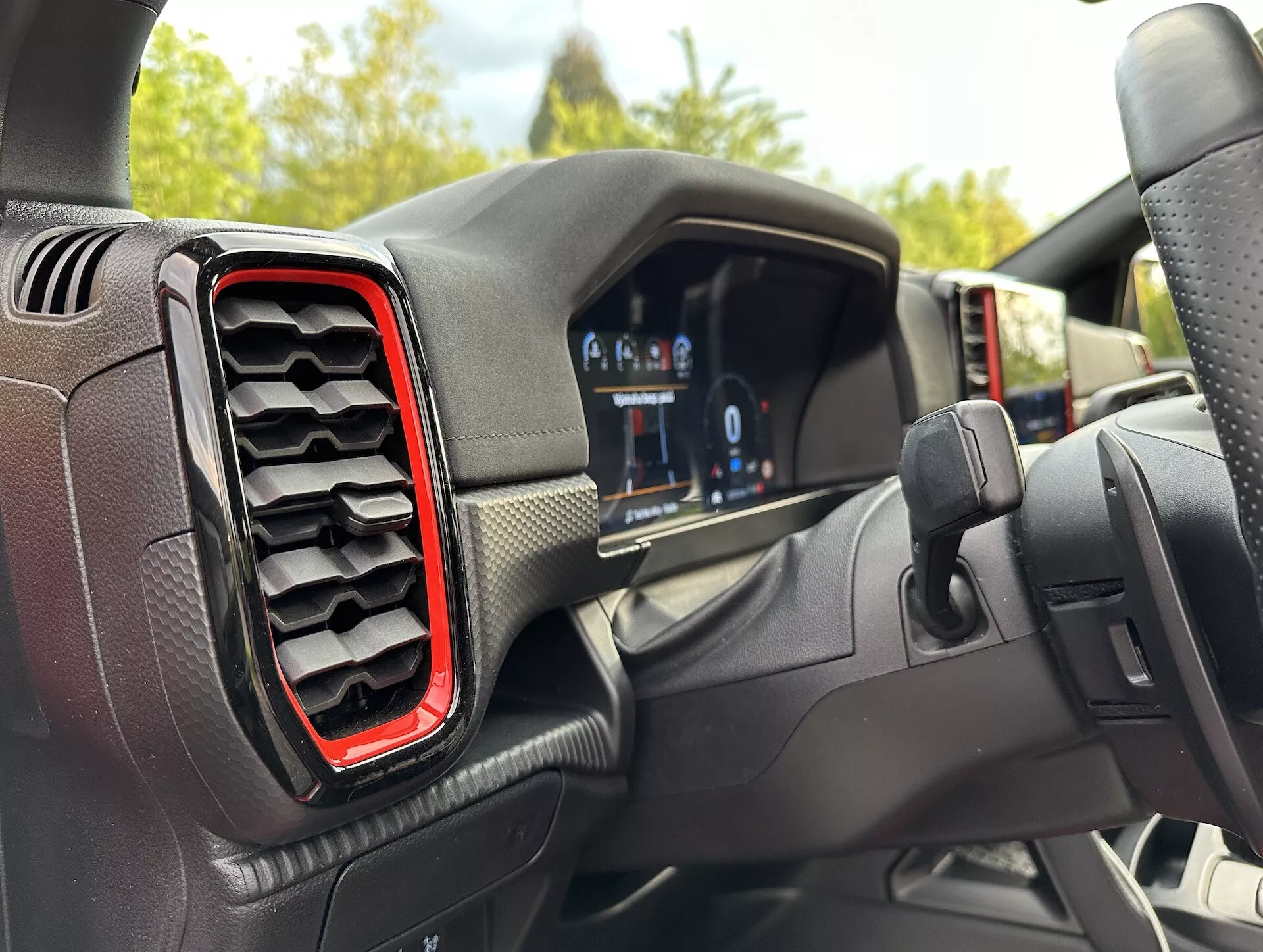 Vue intérieure du Ford Ranger 2022 du point de vue du conducteur, mettant en vedette le tableau de bord numérique et l'aérateur gauche accentué de rouge, avec un angle légèrement décentré vers le volant suggérant un tournant