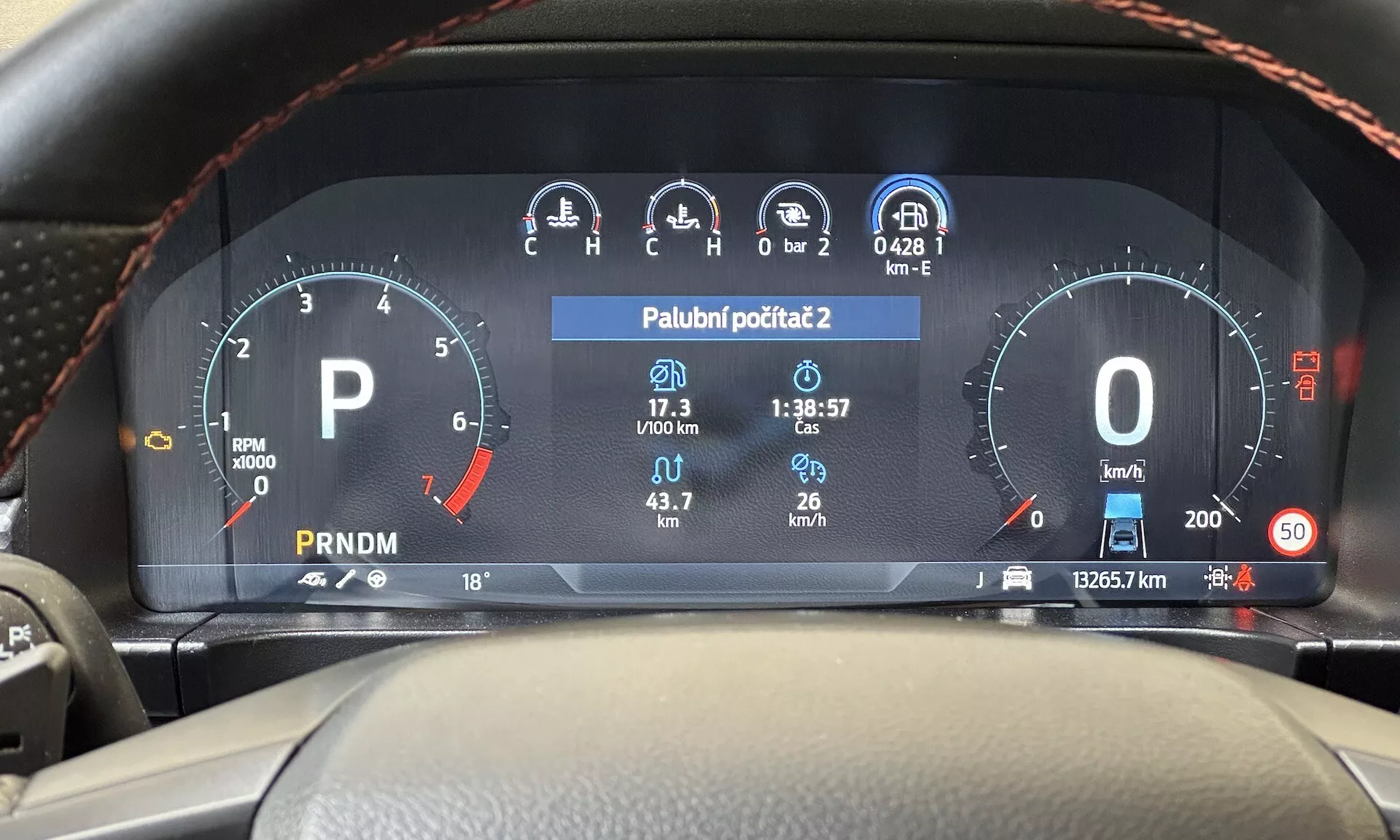 Vue du poste de conduite sur le tableau de bord numérique du Ford Ranger 2022 affichant le compte-tours, le jauge de carburant, le compteur de vitesse, l'affichage de la température, et le sélecteur de vitesse sur un tableau de bord moderne de véhicule