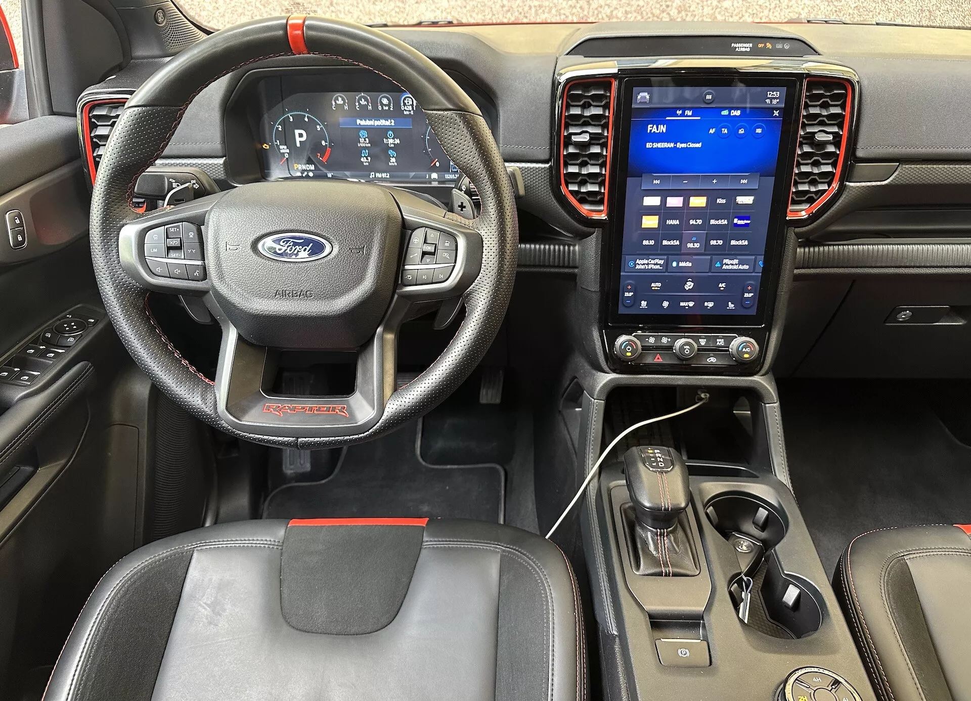 Vue de l'intérieur du Ford Ranger 2022 montrant la perspective du conducteur, avec un volant à trois branches avec commandes, tableau de bord numérique et système d'infodivertissement tactile vertical sur le tableau de bord