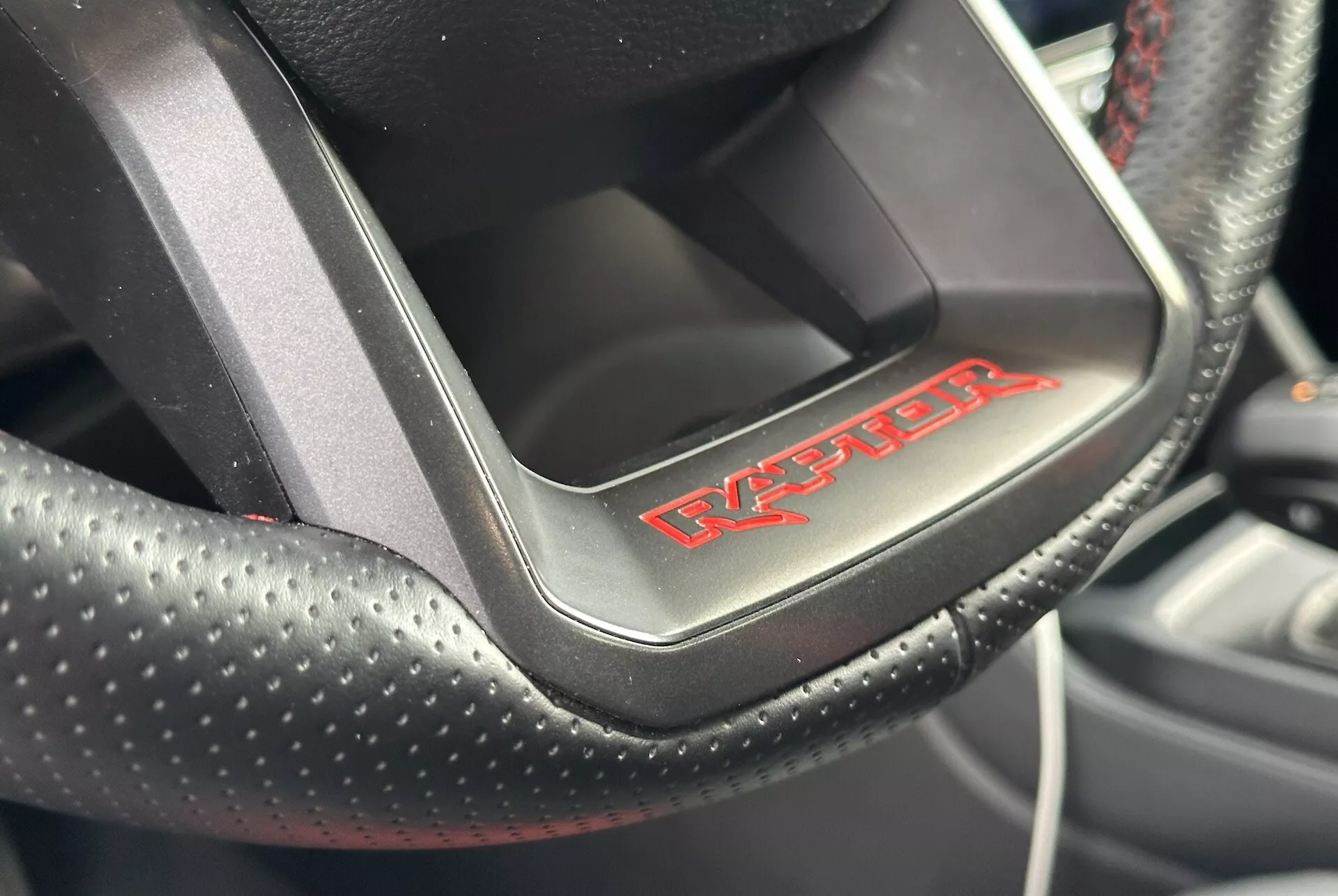 Vue rapprochée d'un volant de Dodge Viper montrant le cuir perforé avec couture rouge et le badge 'Viper', indiquant un intérieur de voiture sportive et luxueux.