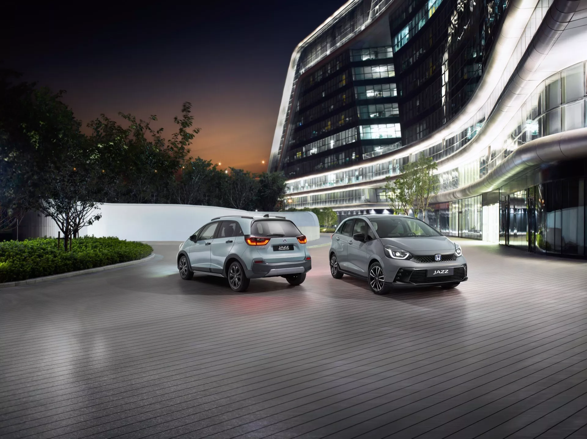 Honda Jazz 5ème génération facelift 2023 exposée dans un environnement urbain de luxe au crépuscule, présentant des caractéristiques de conception avancées et une technologie d'éclairage