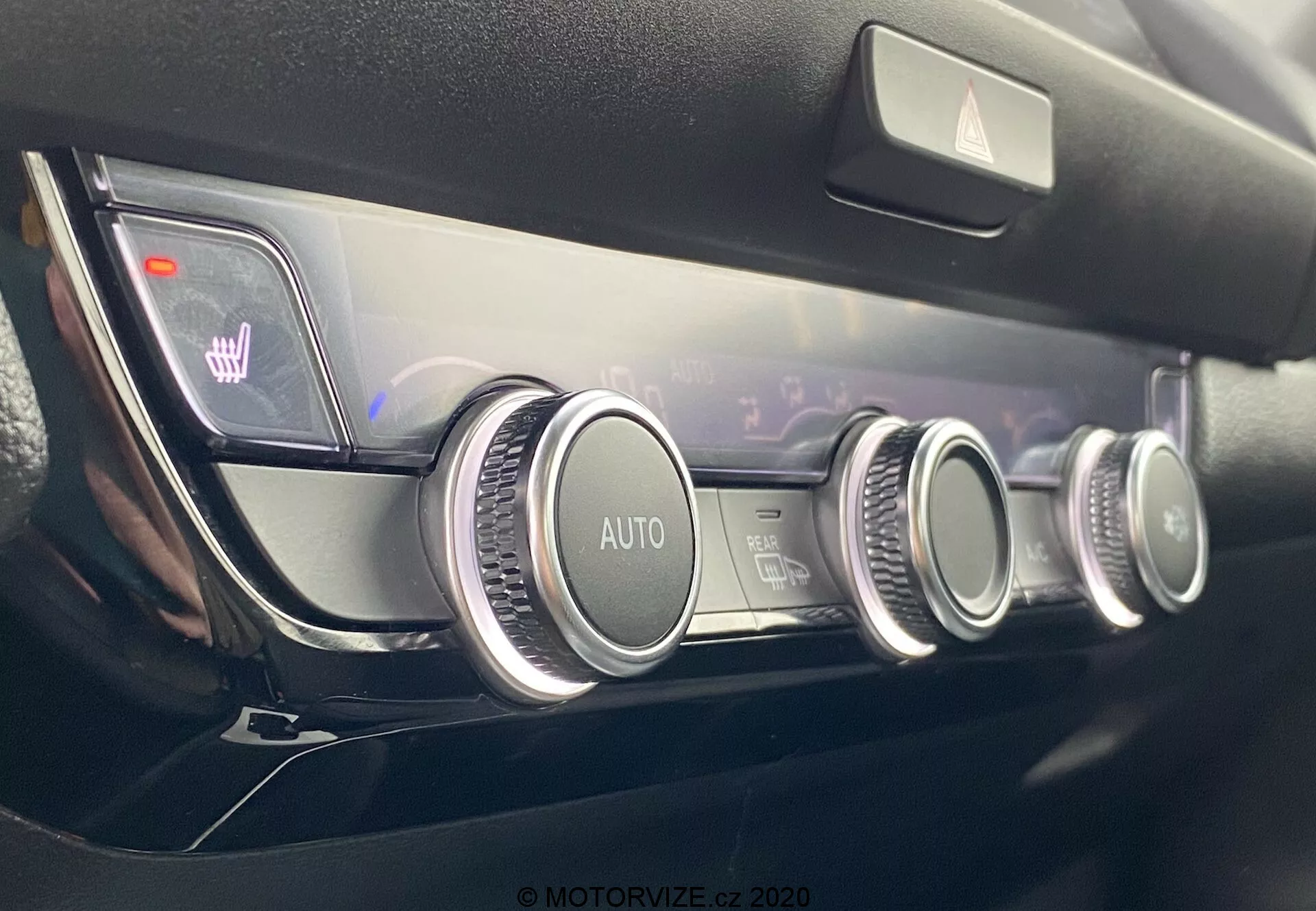 Vue rapprochée du panneau de contrôle climatique moderne de la Honda Jazz 2020 avec trois cadrans circulaires à finition métallique, un système de contrôle automatique du climat, des réglages de température à double zone indiqués sur un affichage numérique et des icônes de chauffage de siège éclairées, le tout dans un design minimaliste et de haute qualité du tableau de bord.