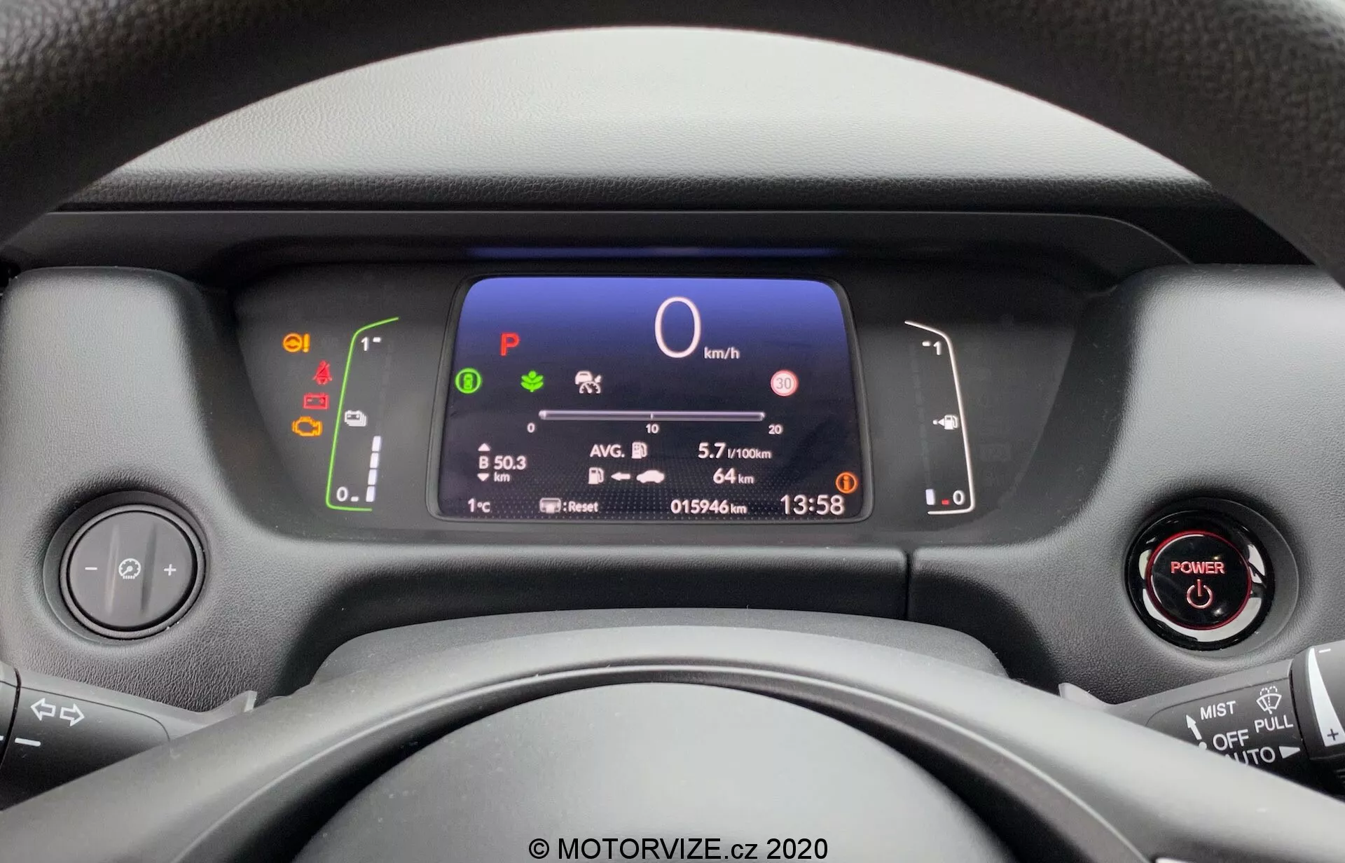 Vue depuis le siège conducteur d'une Honda Jazz 2020, accentuée sur le tableau de bord moderne, le volant et les commandes du tableau de bord. L'affichage numérique montre des informations clés sur le véhicule, y compris la vitesse, la sélection des rapports, l'efficacité du carburant, l'heure et la température, avec un démarrage sans clé et des commandes multifonctions sur le volant visibles.