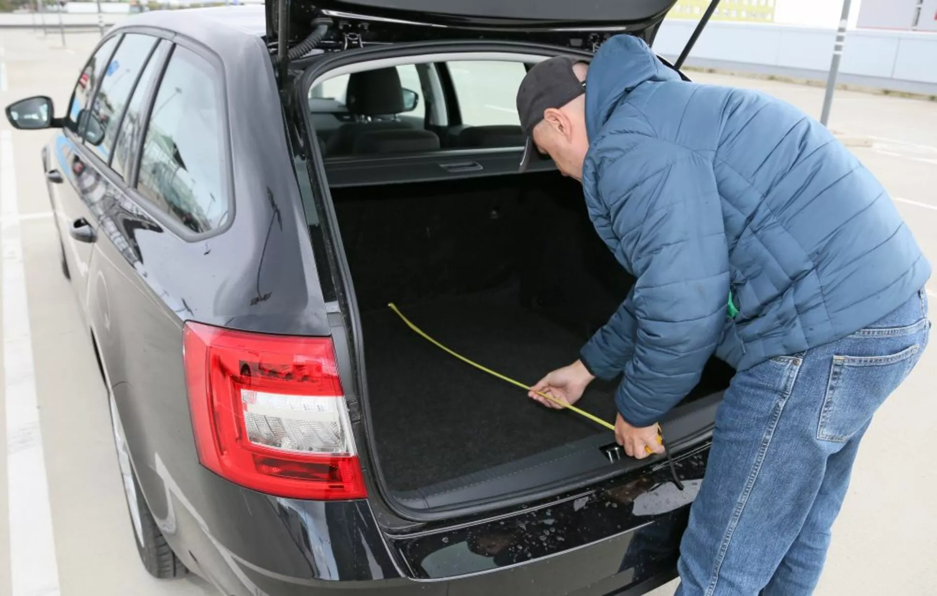 Hyundai i30 2017 (i30-N) présentant son coffre spacieux avec intérieur doublé de tissu, doté de feux arrière LED modernes et d'une personne mesurant l'espace du coffre, capturée sous un angle de trois quarts à la lumière du jour en extérieur