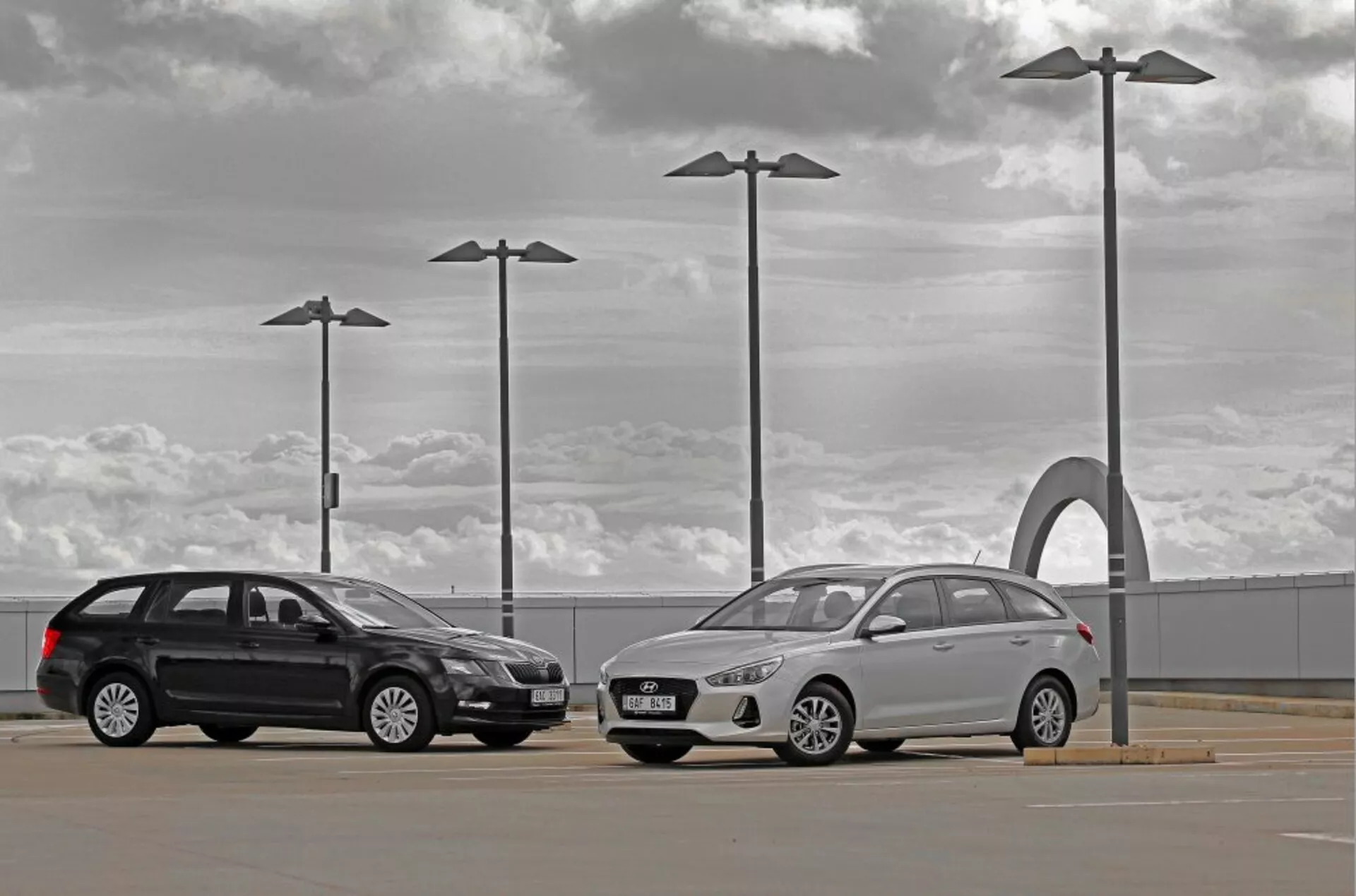 Hyundai i30 2017 break et berline dans un parking extérieur sous un ciel nuageux avec des éléments de design urbain