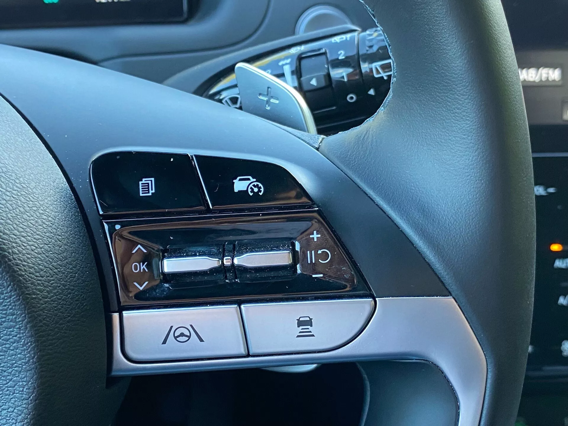 Vue en gros plan des commandes montées sur le volant du côté gauche d'une Hyundai Tucson 1.6 T-GDI Pure 2020, montrant des fonctionnalités telles que la navigation dans les menus, le contrôle du volume audio, l'activation des commandes vocales et la connectivité téléphonique via Bluetooth.