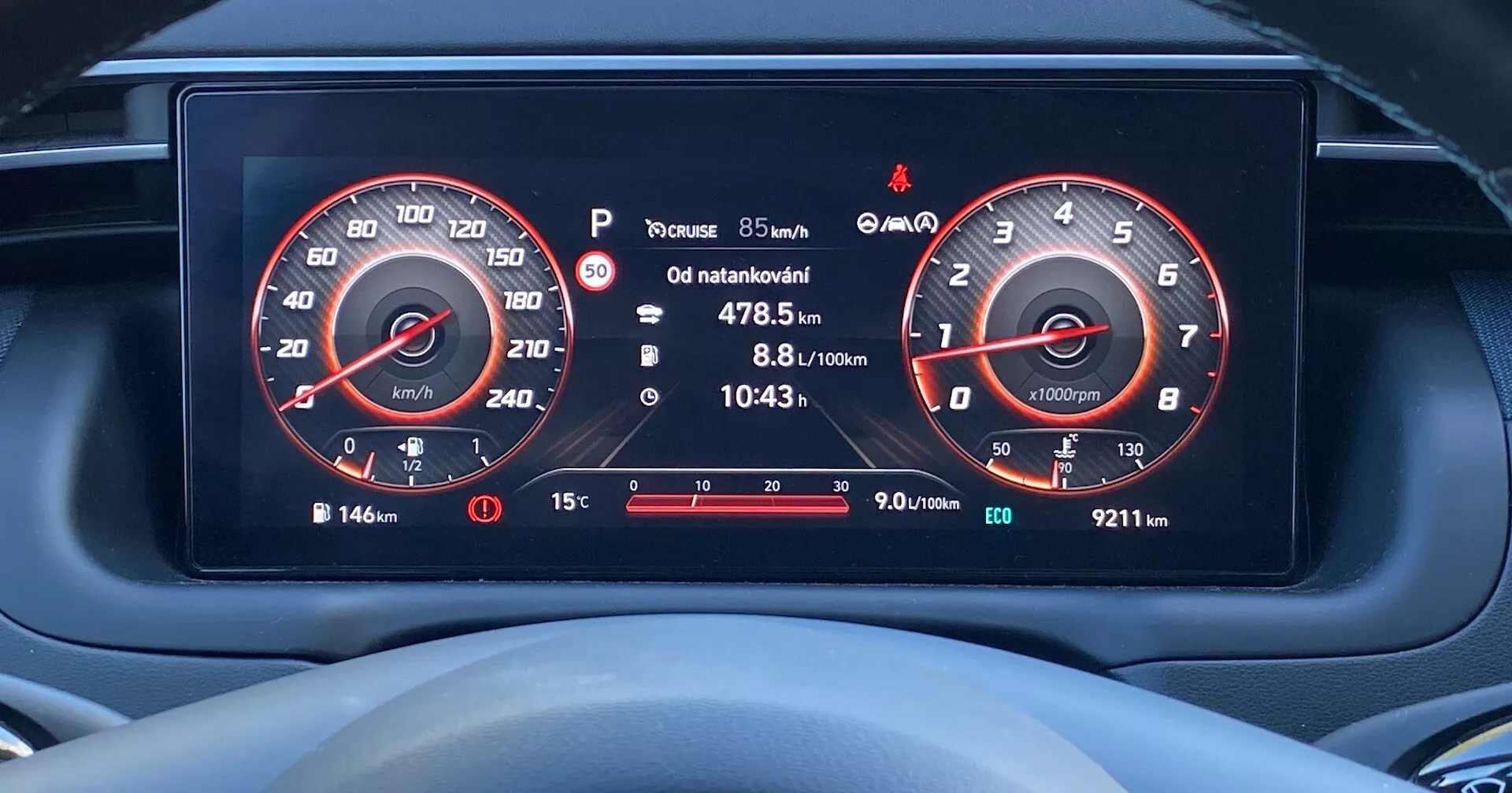 Vue rapprochée du tableau de bord numérique d'une Hyundai Tucson 2020 depuis la perspective du conducteur, affichant des écrans haute résolution du compteur de vitesse (jusqu'à 260 km/h) et du compte-tours (jusqu'à 7000 tr/min), jauge de carburant, informations du trajet, avertissement de pression des pneus, température extérieure et diverses icônes d'avertissement.