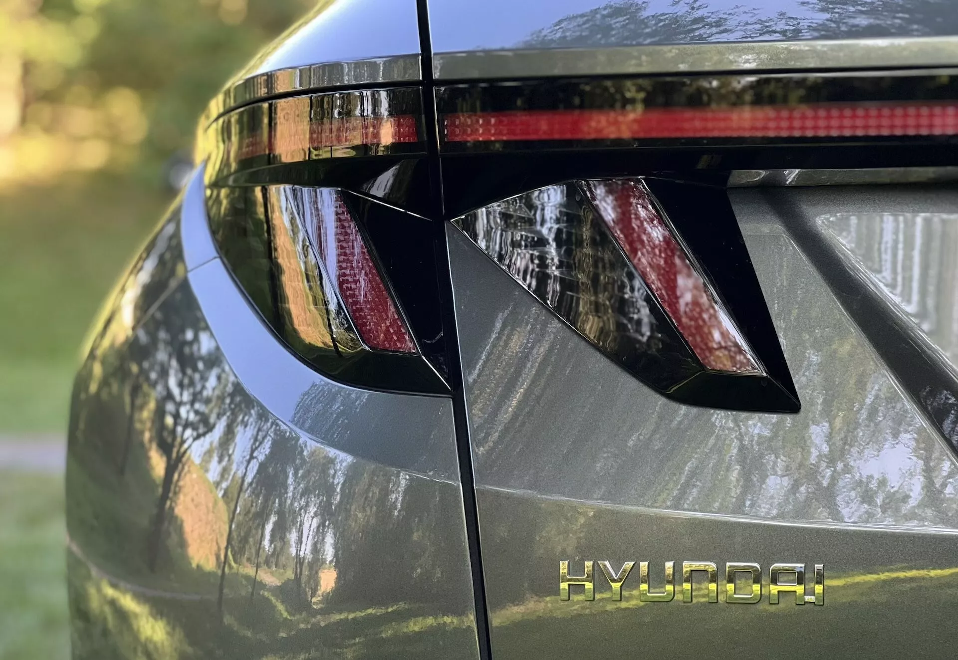 Vue rapprochée de la section arrière de la Hyundai Tucson 2020, présentant des feux arrière LED angulaires, marquage HYUNDAI, spoiler arrière intégré avec feu stop, et finition métallique brillante