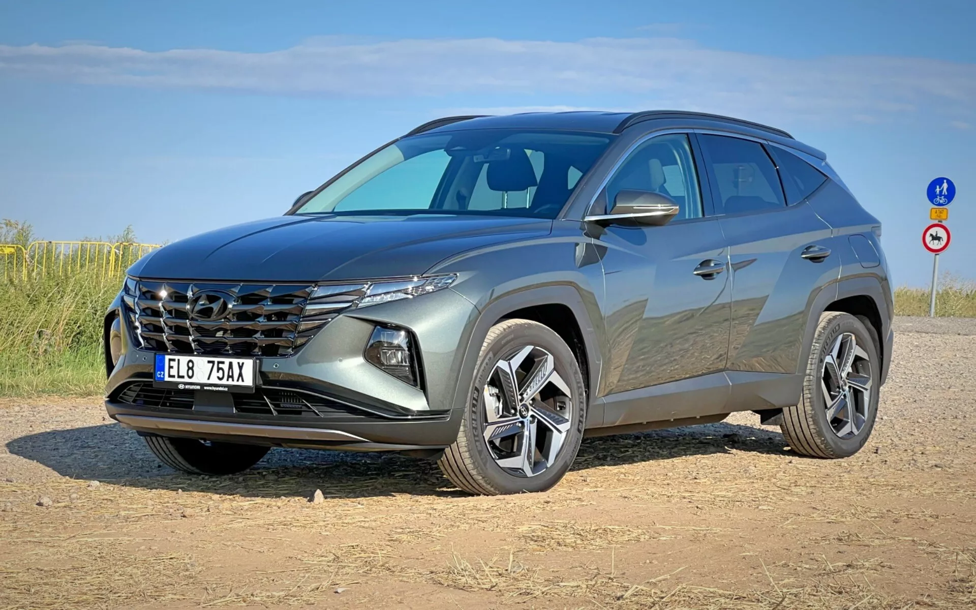 SUV moderne Hyundai Tucson 2020 illustré en vue avant trois quarts mettant en avant sa grille distinctive, ses phares élégants, sa façade avant, son capot sculpté et ses jantes alliage sur un bas-côté en terre sous un ciel clair