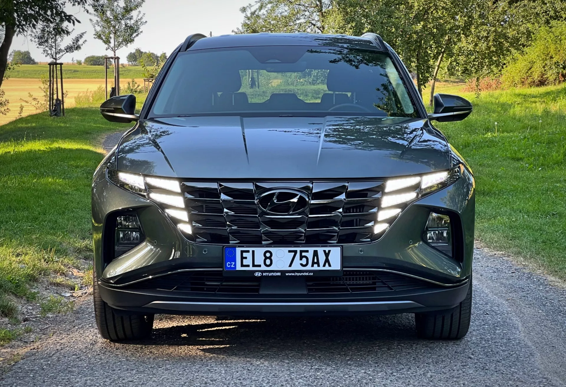 Hyundai Tucson 2020 vue de l'avant sous un angle bas, mettant en avant son design moderne avec lignes angulaires, phares à LED, calandre en cascade et systèmes avancés d'aide à la conduite dans un cadre rural lumineux de jour