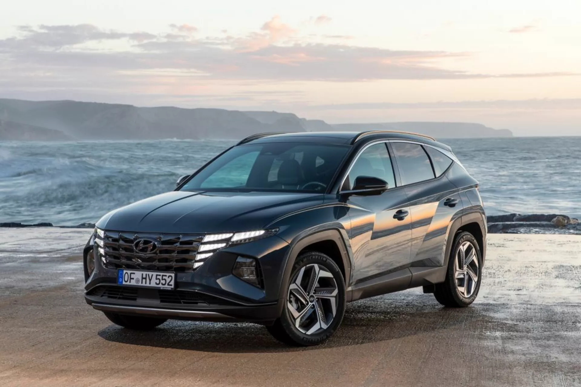 SUV moderne Hyundai Tucson 2020 garé sur un front de mer avec horizon et océan en arrière-plan, présentant sa vue avant trois quarts soulignant la conception du véhicule, la grille proéminente avec logo, les phares LED angulaires et les roues en alliage sportives