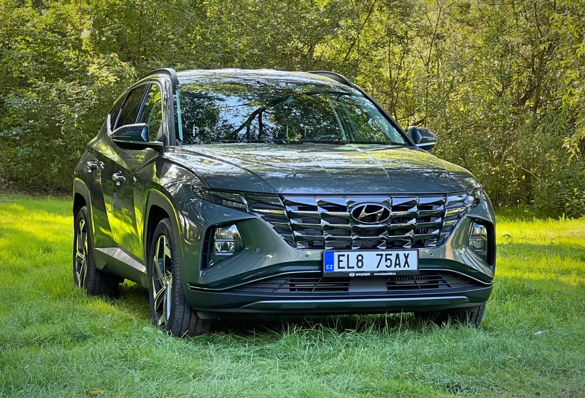 SUV Hyundai Tucson 2020 avec finition métallique, présentant des phares à LED, une grille avant proéminente, un design de capot sculpté, des roues en alliage, et des rétroviseurs latéraux avec clignotants intégrés, garé sur l'herbe soulignant sa capacité tout-terrain