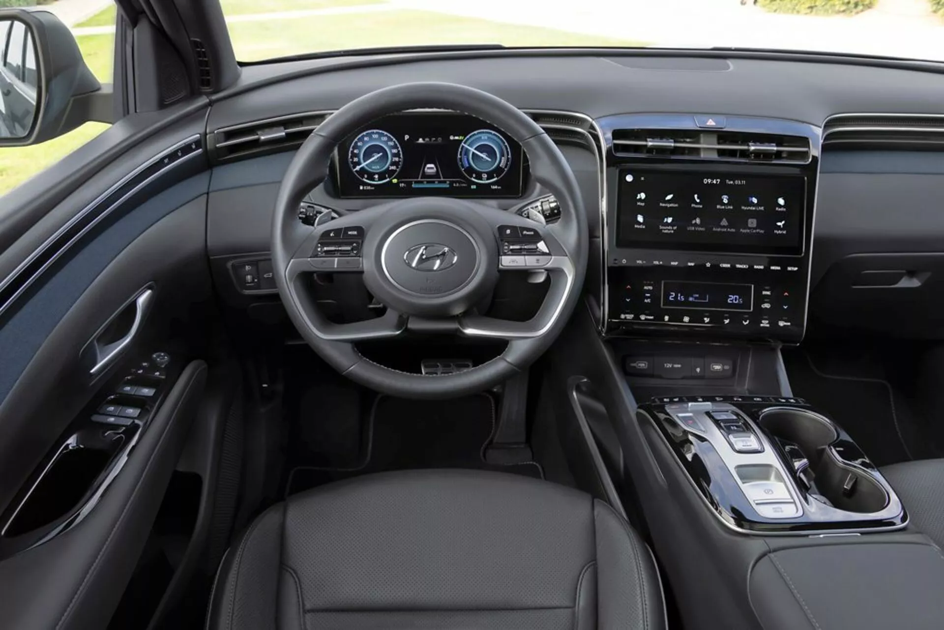 Vue intérieure du Hyundai Tucson 2020 depuis le point de vue du conducteur, mettant en évidence tableau de bord, volant multifonctions avec logo Hyundai, tableau d’instruments numérique, système d’infodivertissement avec écran tactile vertical, commandes minimalistes sur la console centrale, sélecteur de vitesse électronique, garniture en cuir et schéma de couleur monochromatique sophistiqué