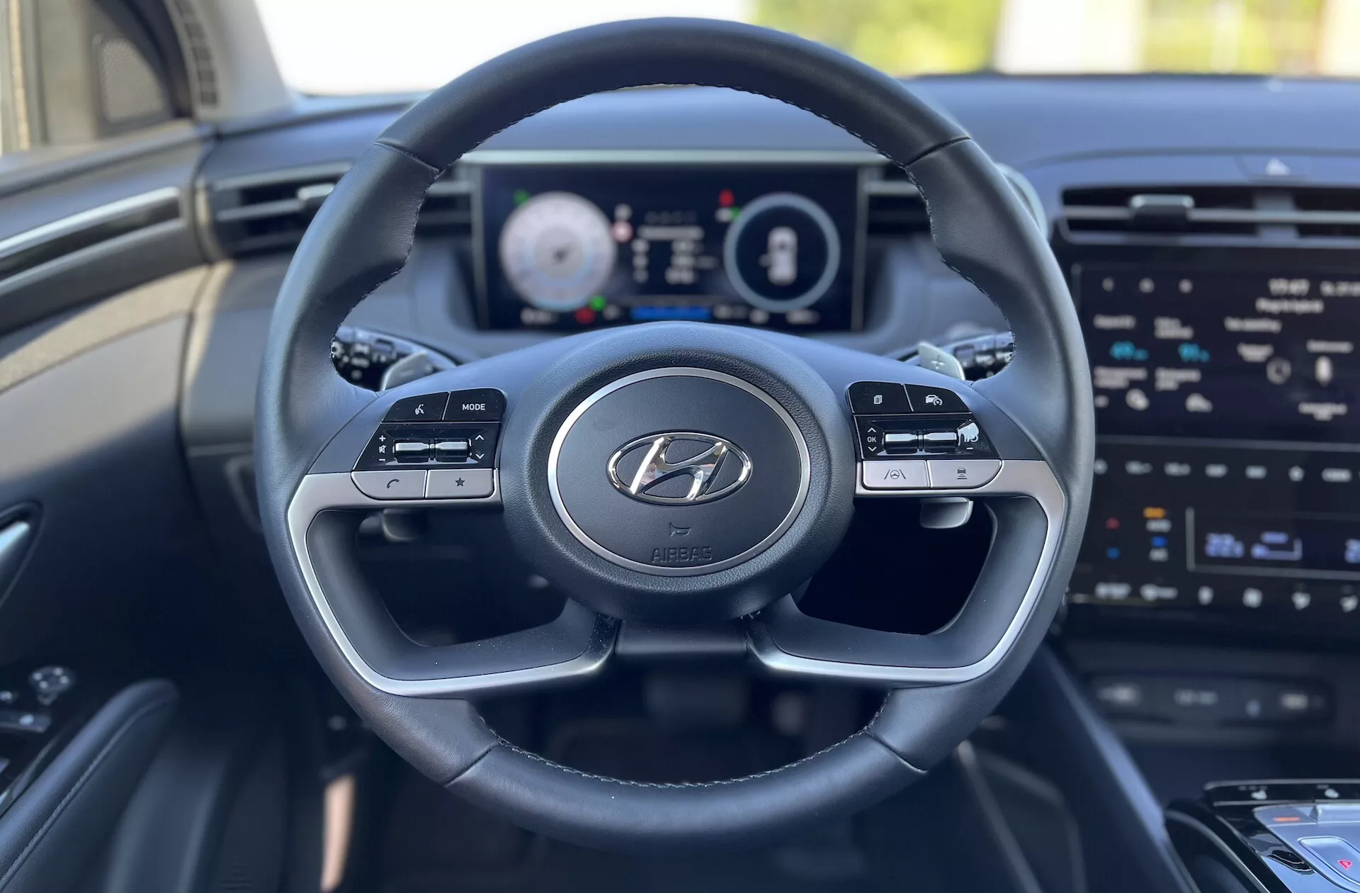 Vue intérieure du Hyundai Tucson 2020 depuis le siège du conducteur montrant le volant avec le logo Hyundai, le tableau de bord numérique et l'écran d'infodivertissement