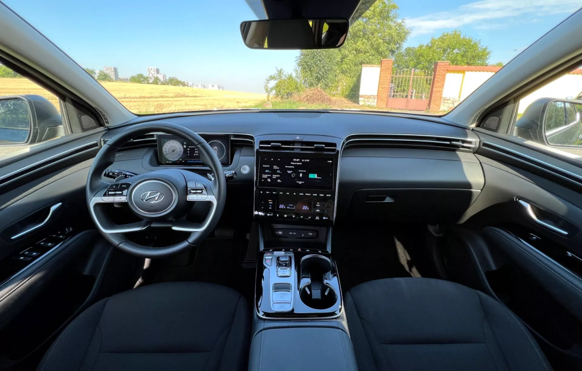 Intérieur du Hyundai Tucson 2020 montrant les sièges avant, le volant avec logo du fabricant et boutons de commande, cluster d'instruments numérique, système d'infodivertissement tactile vertical sur la console centrale, levier de vitesse automatique, et design bicolore du tableau de bord dans une vue au niveau des yeux ressemblant à la perspective du conducteur ou du passager avant