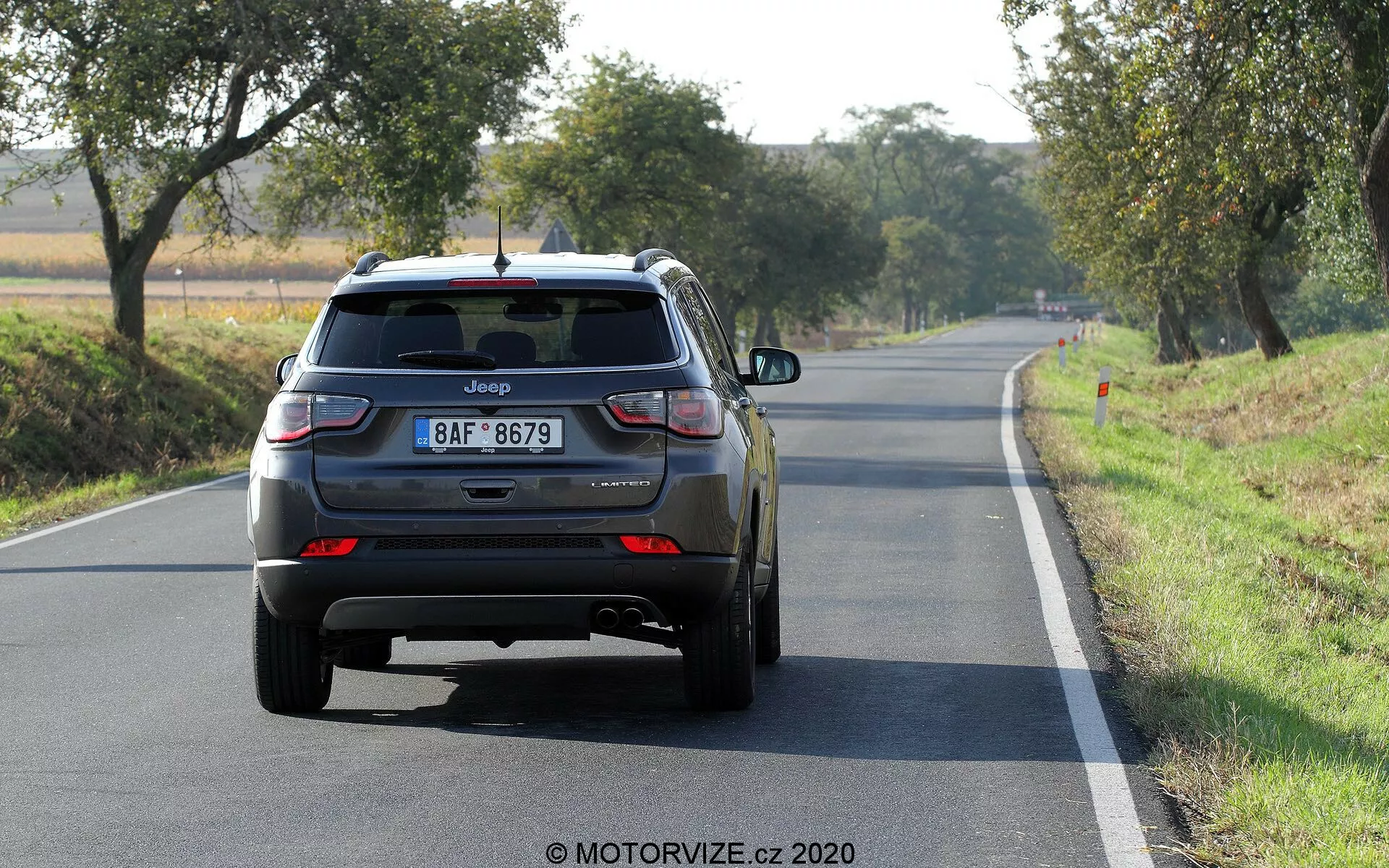 Vue arrière d'un SUV Jeep Compass 2017 sur une route à deux voies en plein jour, marquage visible, nom du modèle, plaque d'immatriculation de style européen, feux arrière à LED, hayon fermé avec essuie-glace arrière, troisième feu stop sur le spoiler arrière, pare-chocs arrière avec réflecteurs, doubles tuyaux d'échappement sur le côté gauche, roues arrière en alliage, badge supplémentaire pouvant indiquer le niveau de finition ou la transmission.